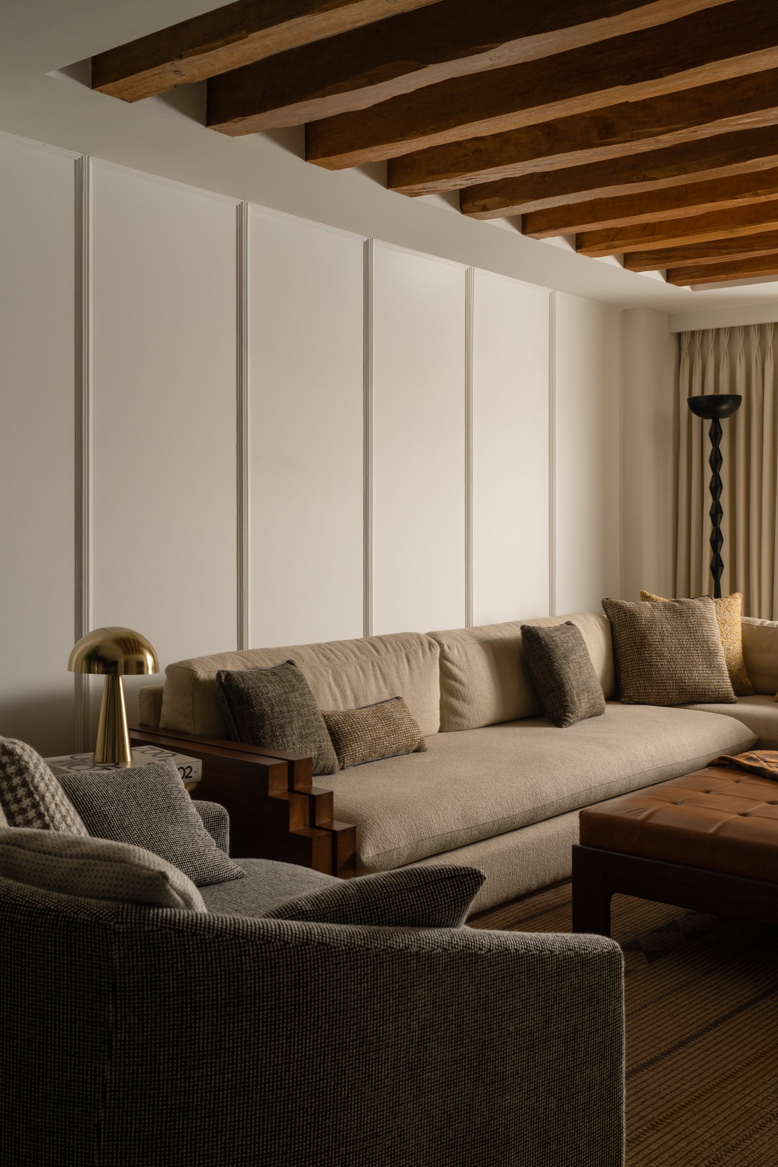 A closer view of the living seating against a reeded panelled wall, with a brass table lamp anchoring one end