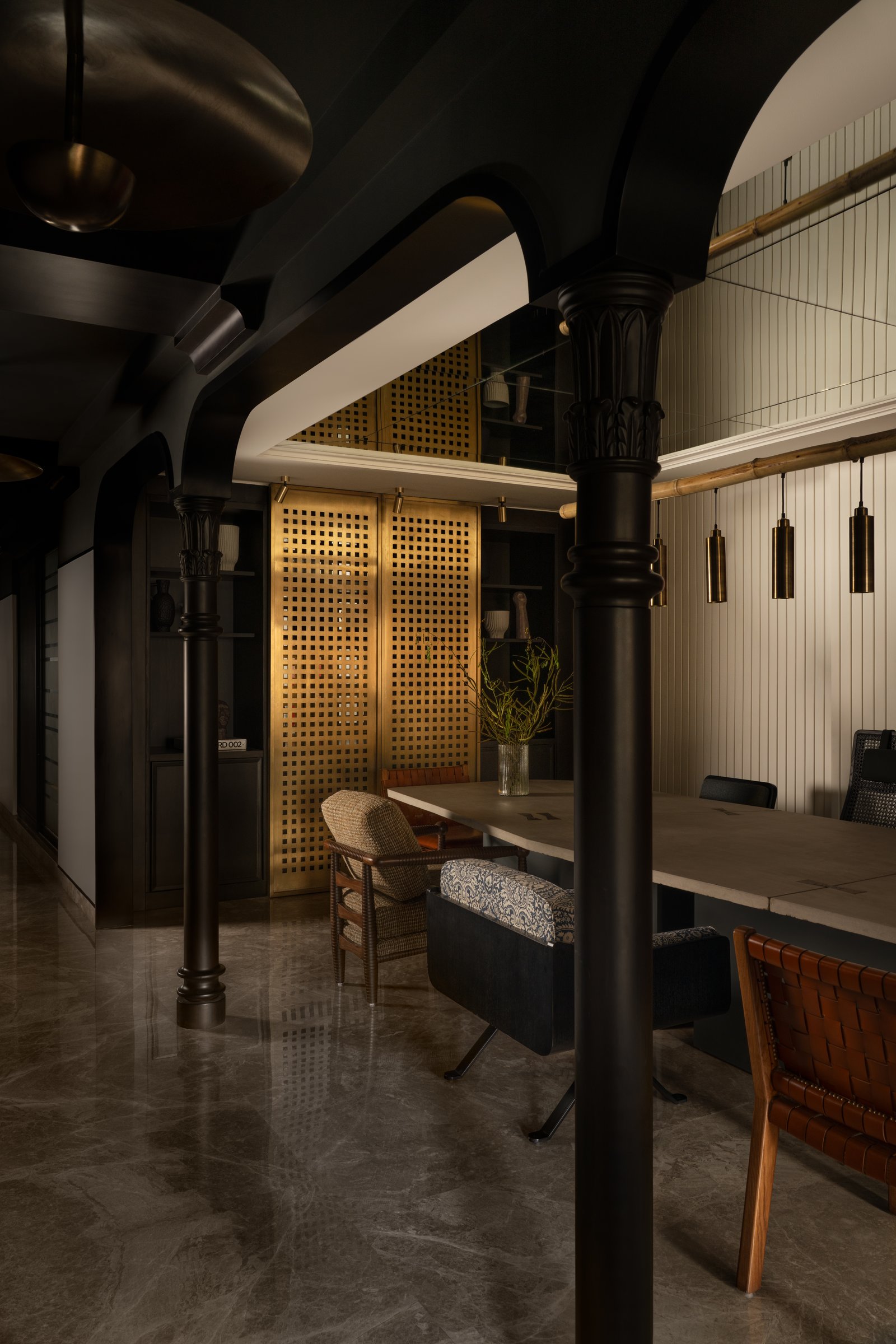 A closer view of the dining, where blackened columns with carved capitals and a glowing brass screen conceal the bar behind