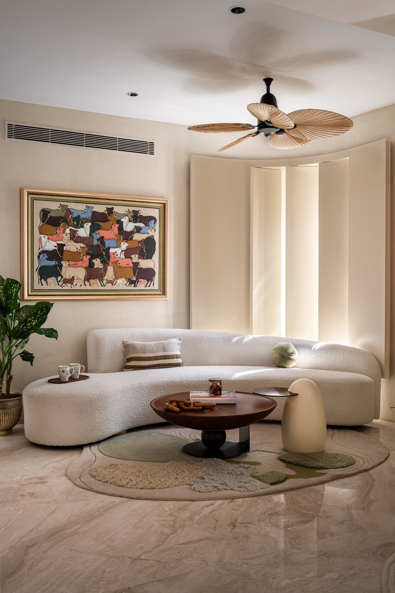 A closer view of the seating group, the sofa's soft geometry meeting a pedestal timber table on a hand-tufted rug in cream and sage