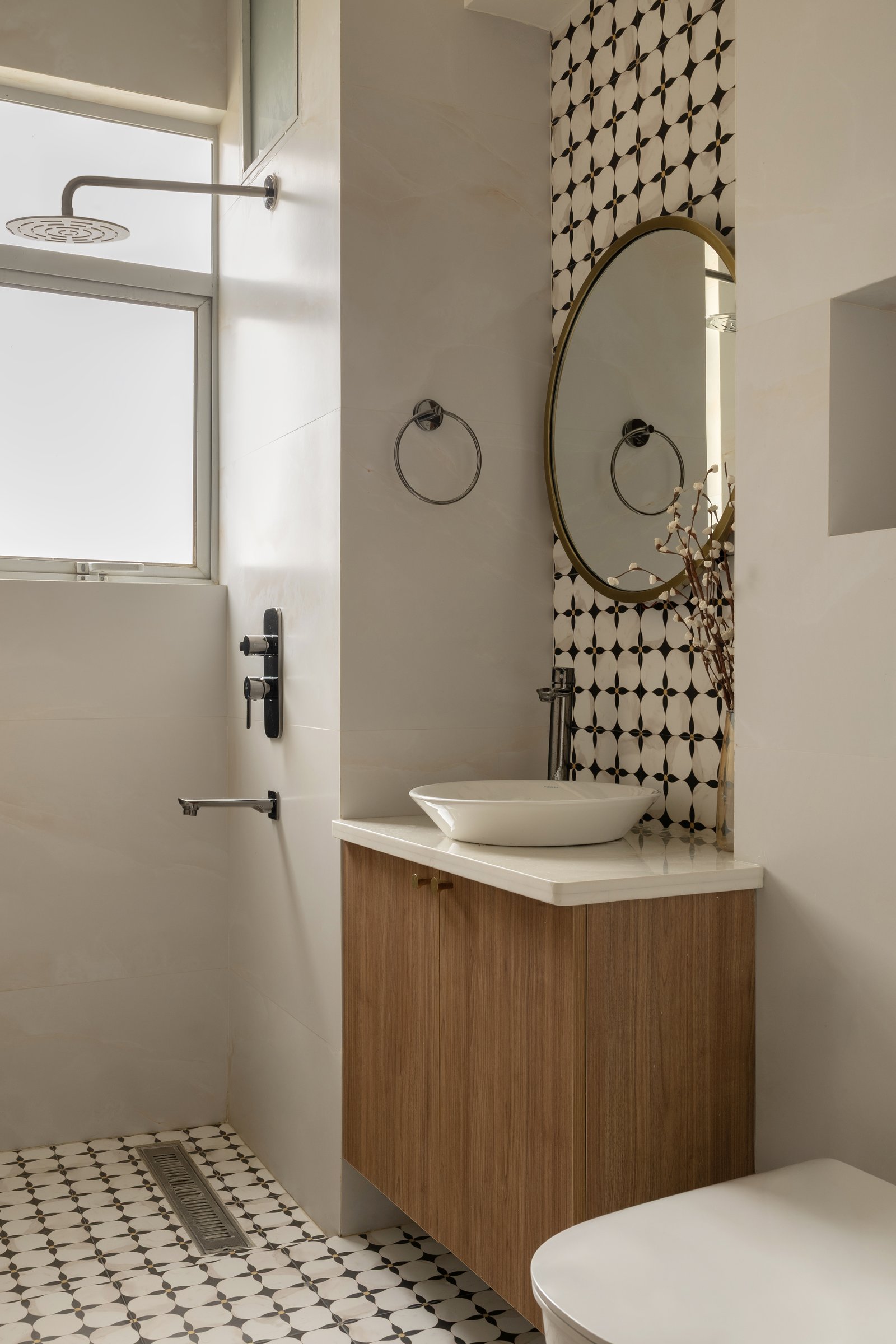 The second bathroom, where a full-height geometric floral tile column anchors a walnut vanity