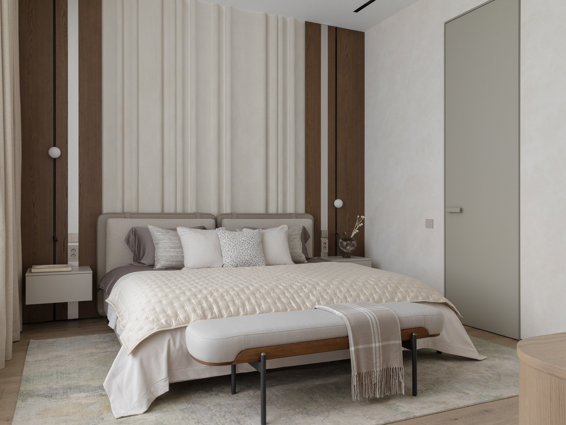 The master bedroom, where a channelled upholstered headboard wall is framed by slim bands of dark oak