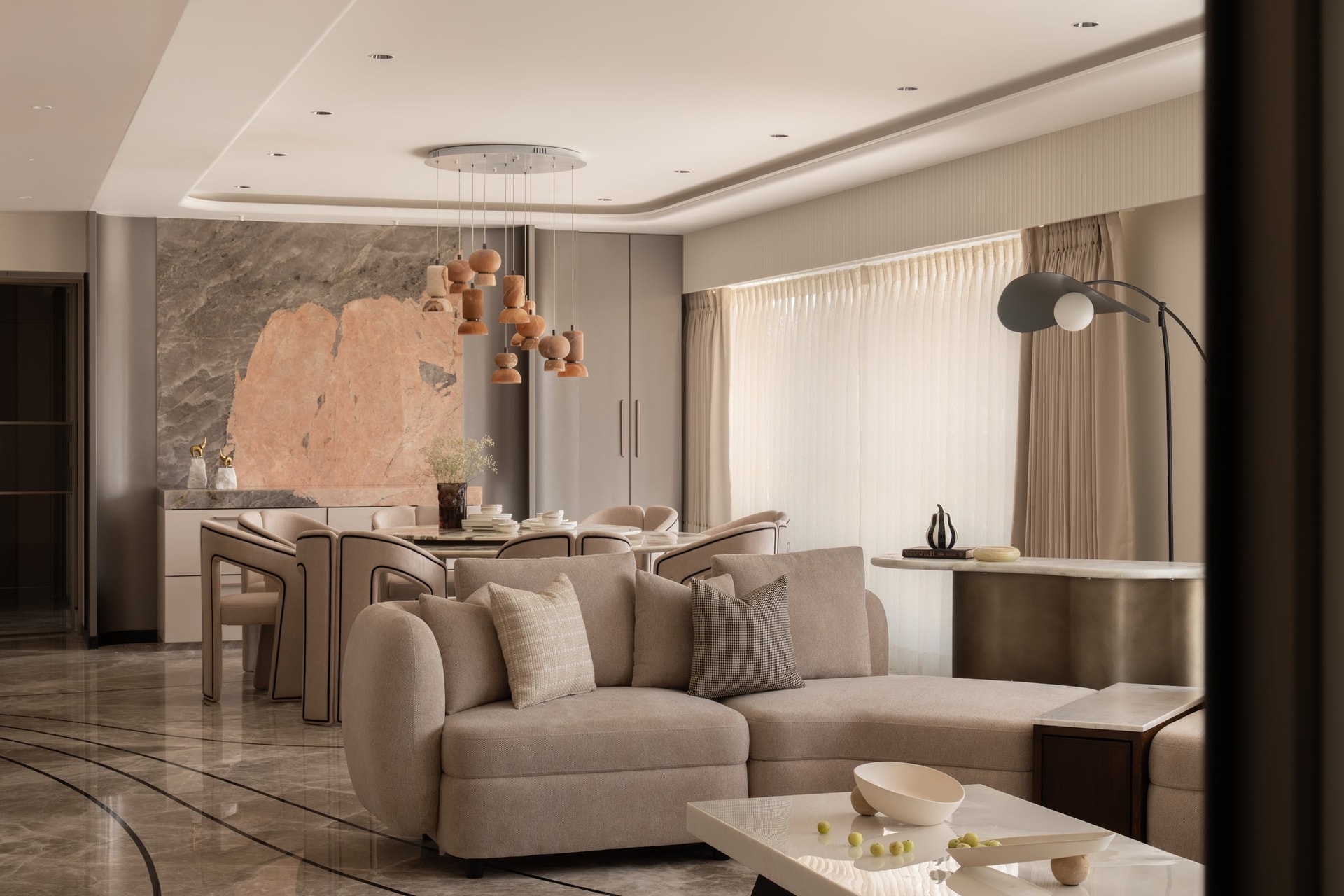 The living and dining rooms, where a veined pink-and-grey stone panel anchors the shared social volume
