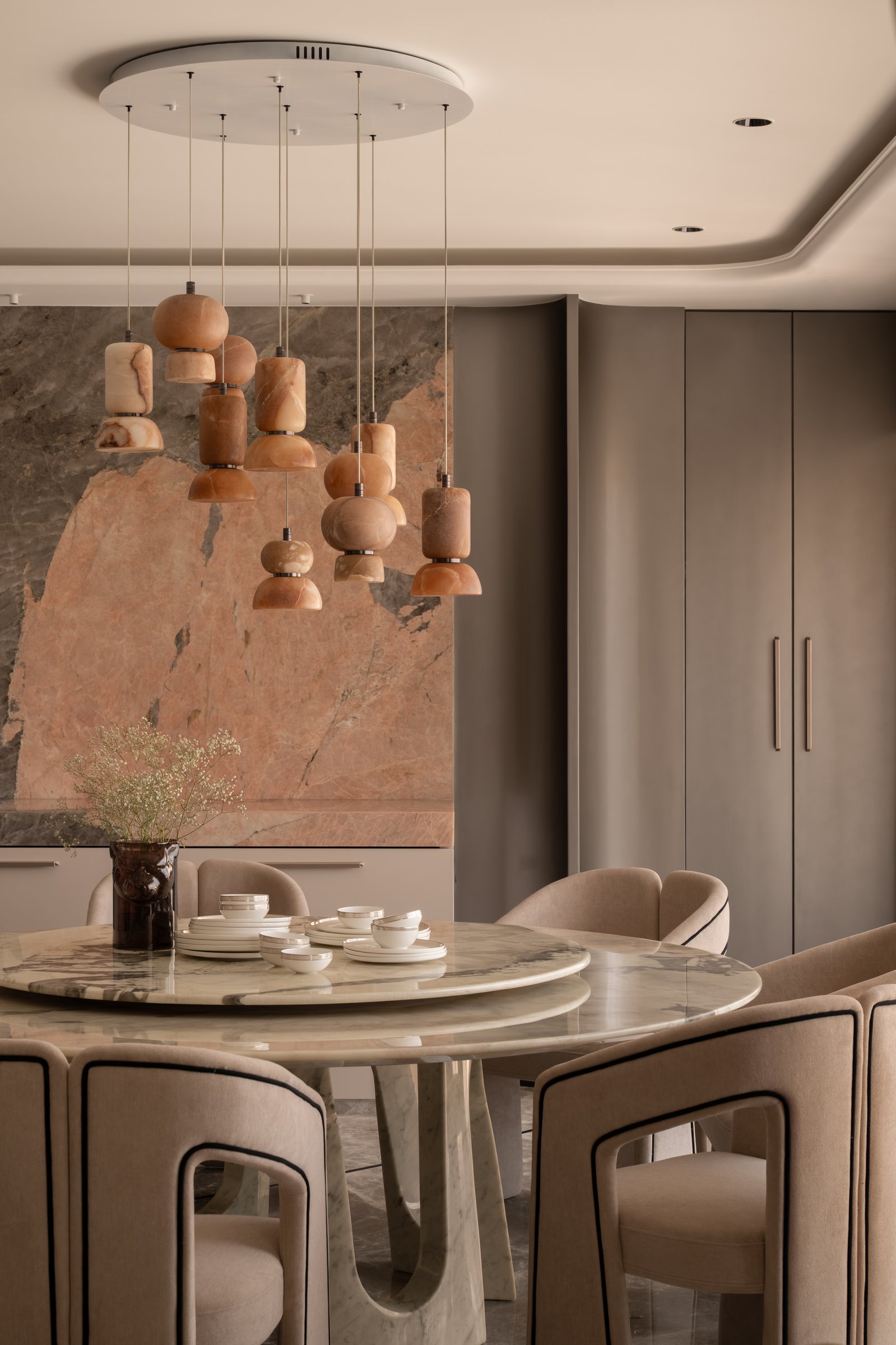 The dining table, where a sculptural marble base and stacked stone pendants reinforce the room's material argument