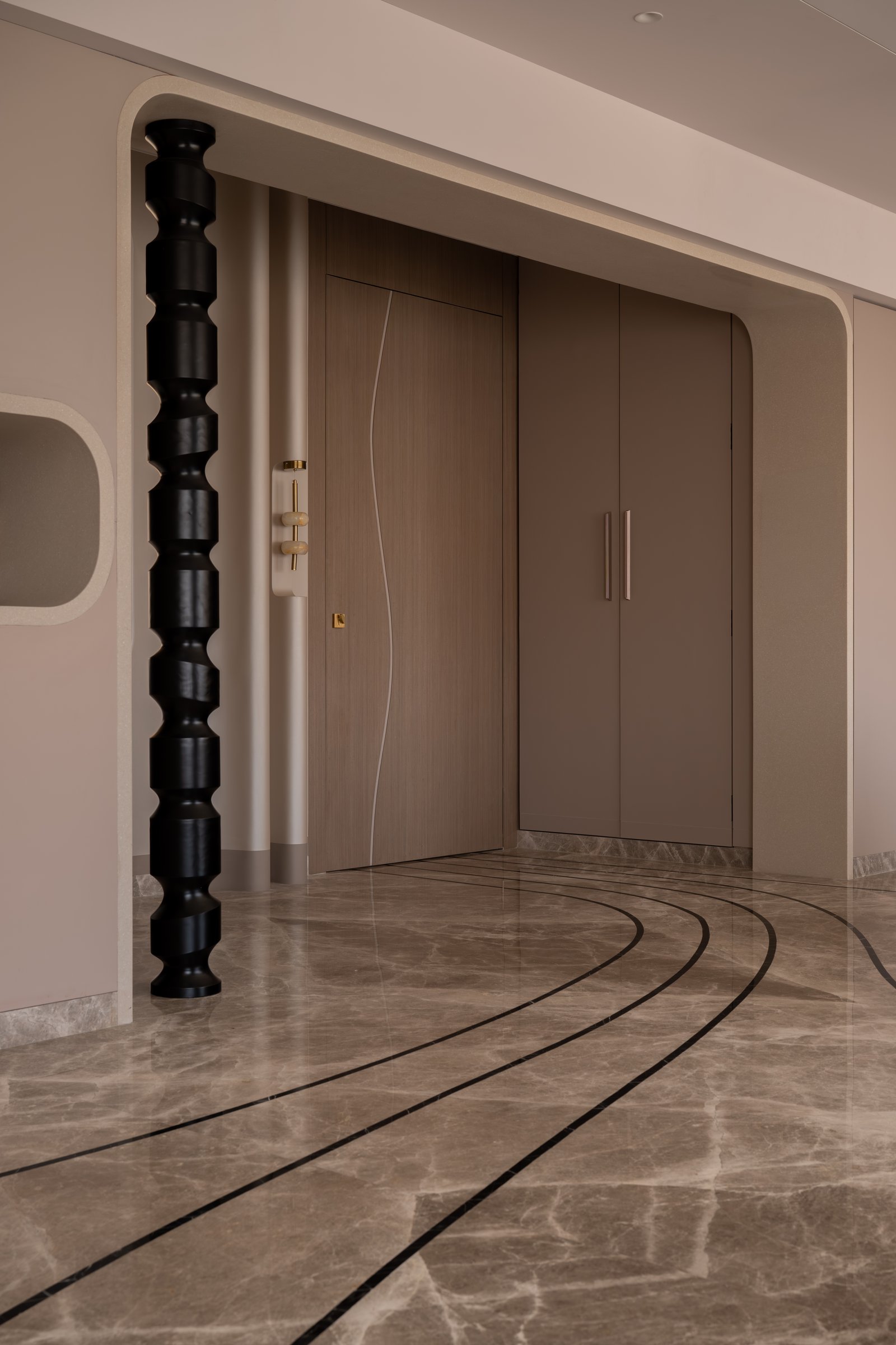 The foyer, where a turned black column and softly arched threshold set the sculptural vocabulary of the home