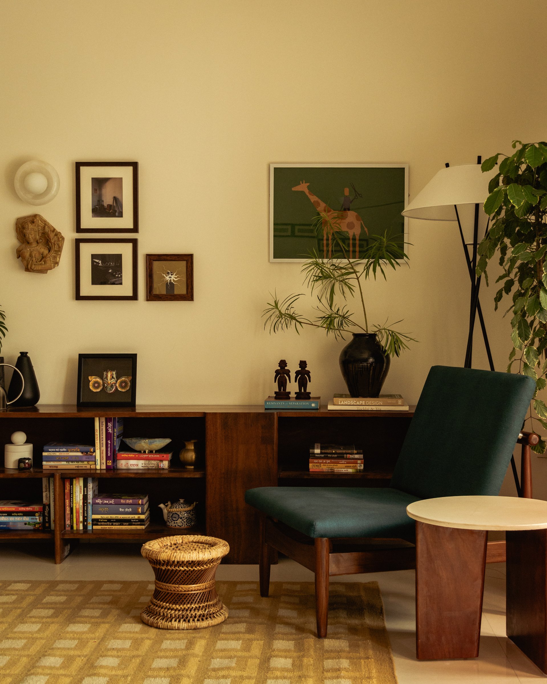 The console wall, where a gallery of framed photographs, a small giraffe artwork, and a teal lounge chair anchor one end of the living area