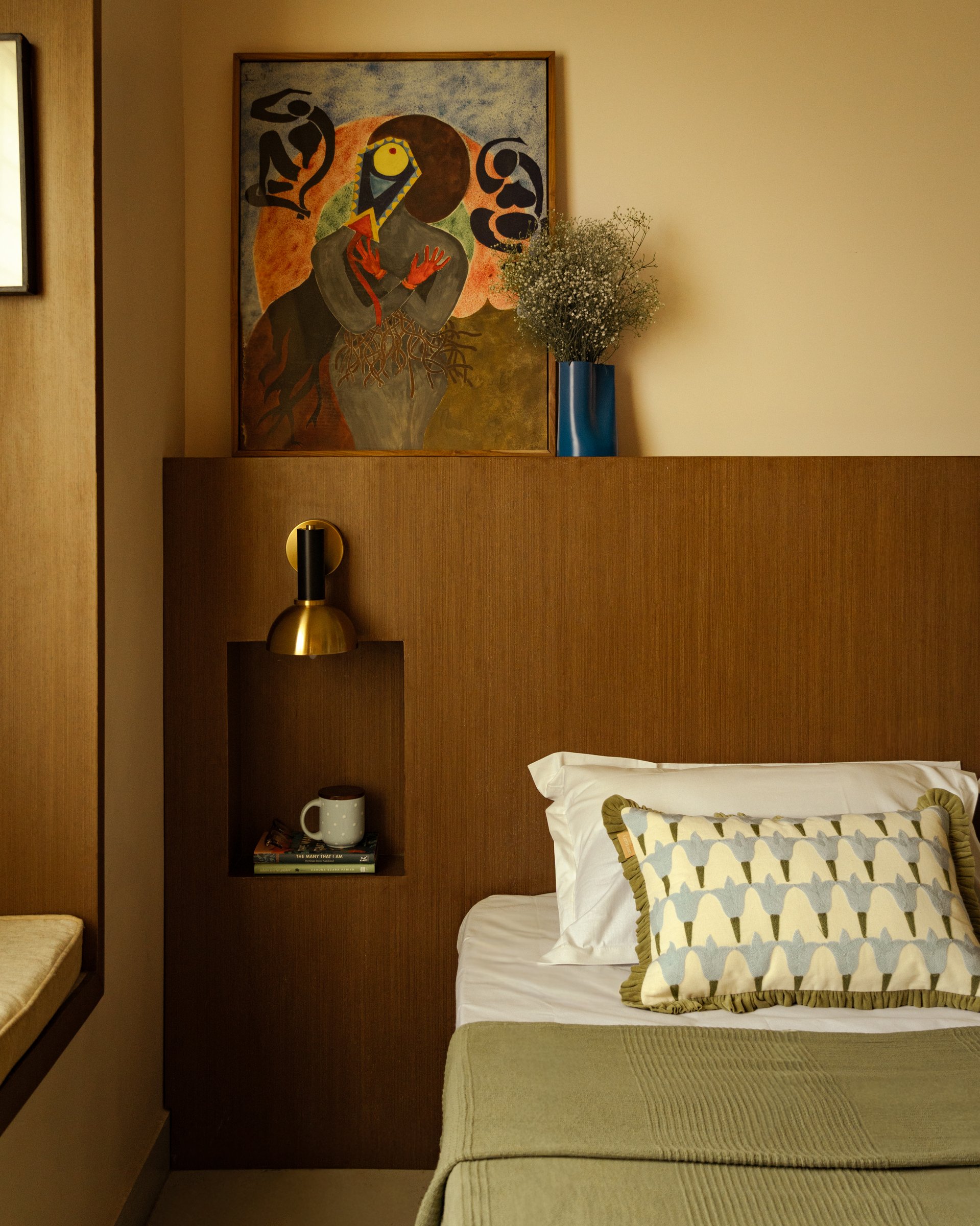 The daughter's bedroom, where a wood-panelled headboard wall carries a niched shelf and an abstract figurative painting
