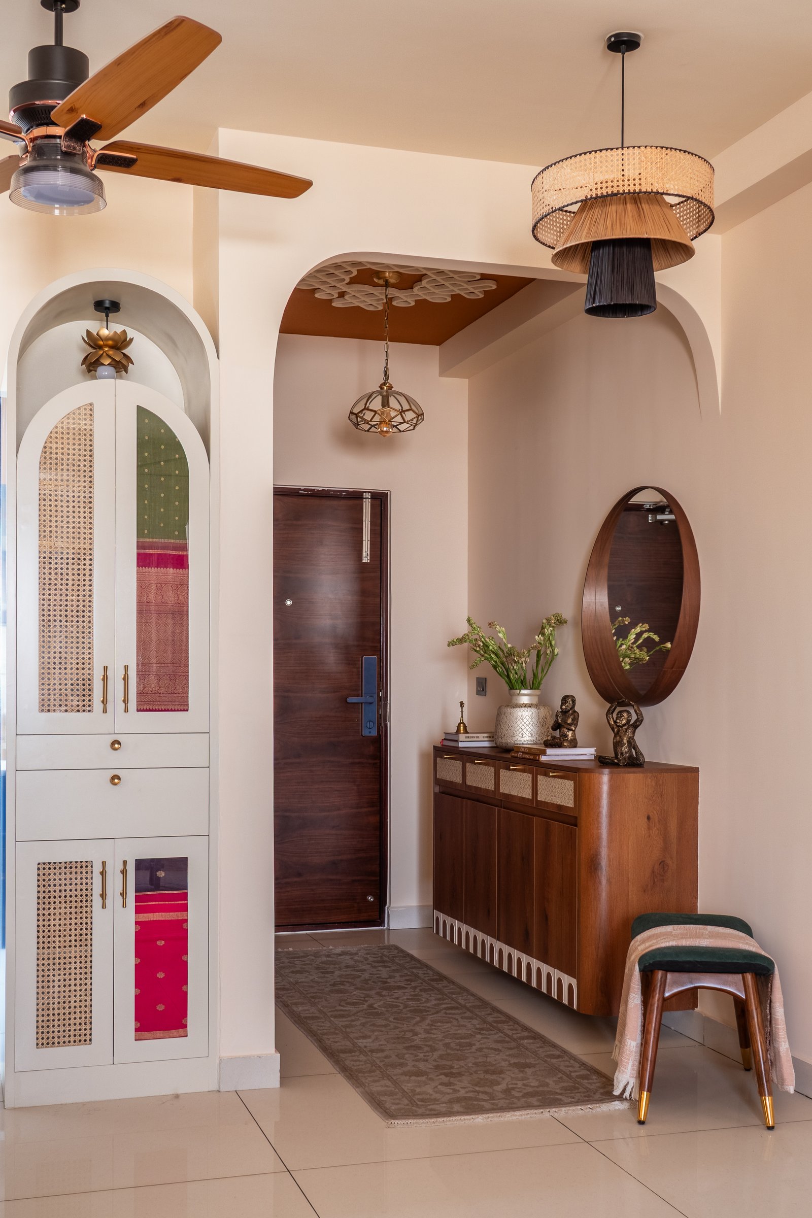The foyer, where a rangoli-inspired ceiling pattern drawn by the client's mother and a Kanjeevaram-fronted storage wall set the home's material and emotional register