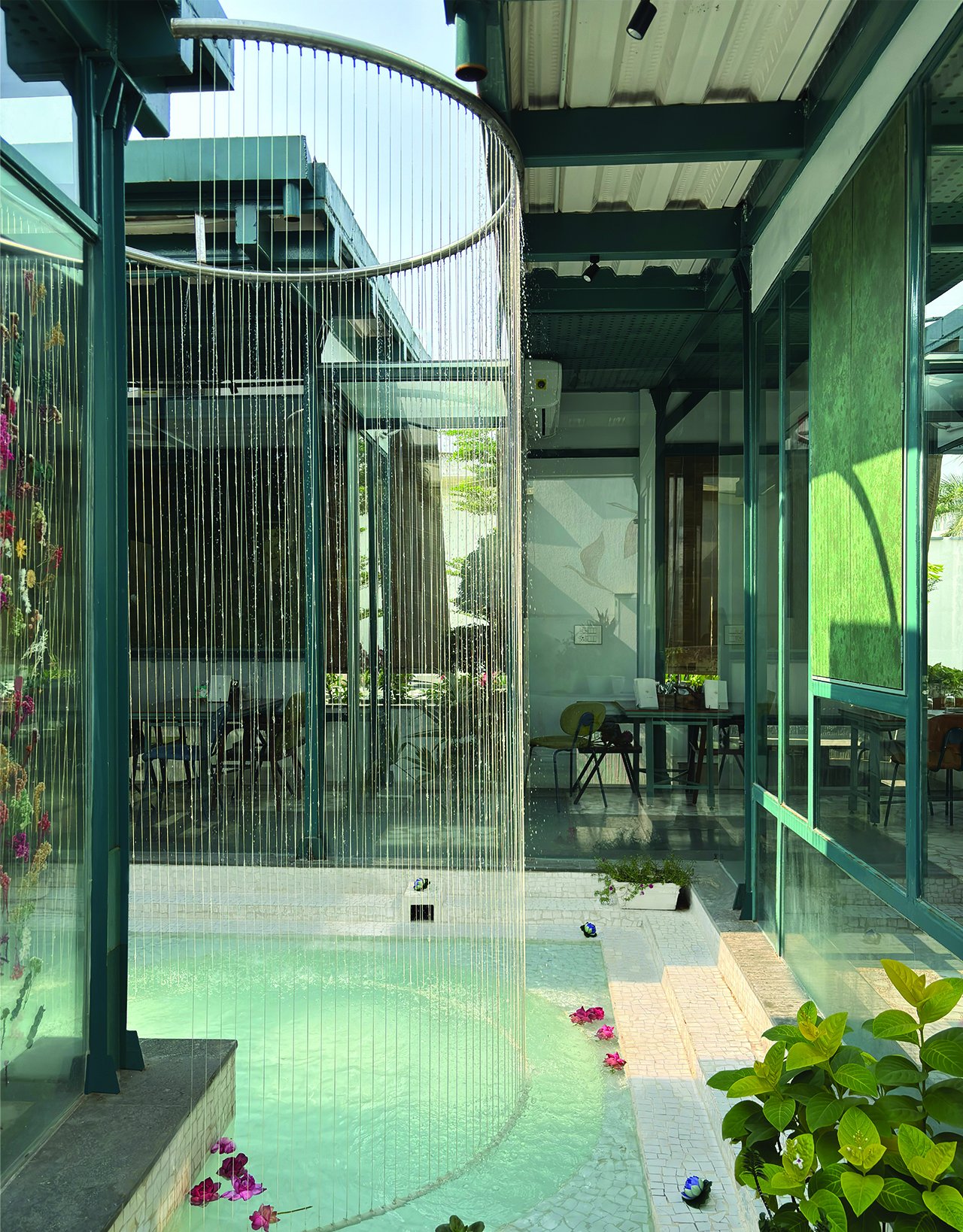 The central water court, where a curtain of fine vertical strands falls from a circular frame overhead and daylight moves across the pool