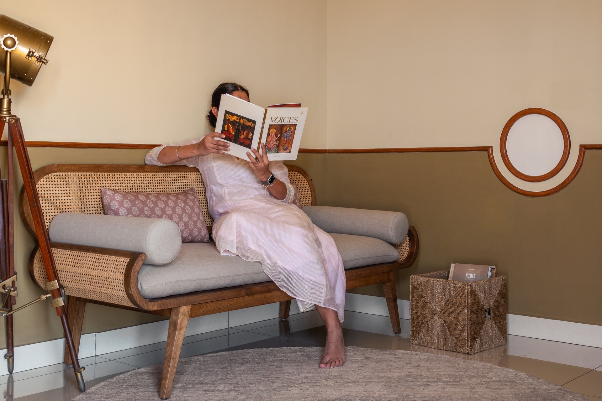 A quiet corner with a cane-backed settee and tripod lamp, designed for the kind of unhurried pause the home is built to hold