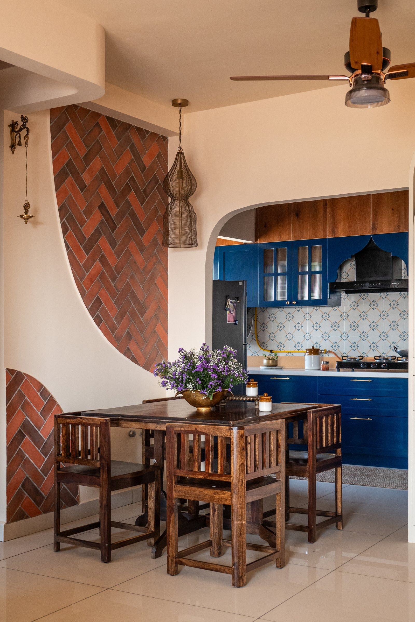 The dining area, where a sweeping arc of herringbone-laid terracotta tiles anchors the transition between living room and kitchen