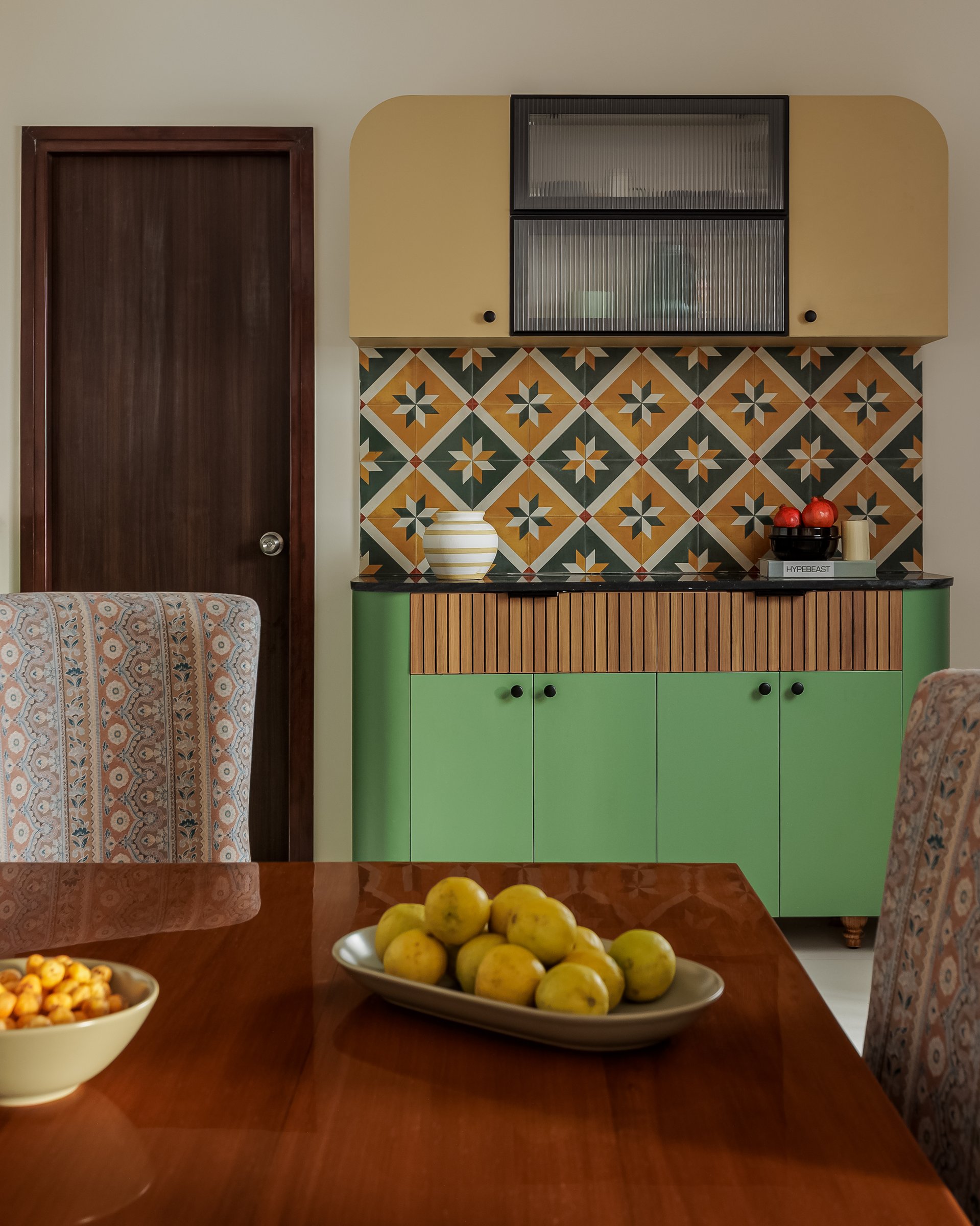 The dining area, where a parrot-green and pastel-yellow crockery cabinet meets a star-motif tile backsplash