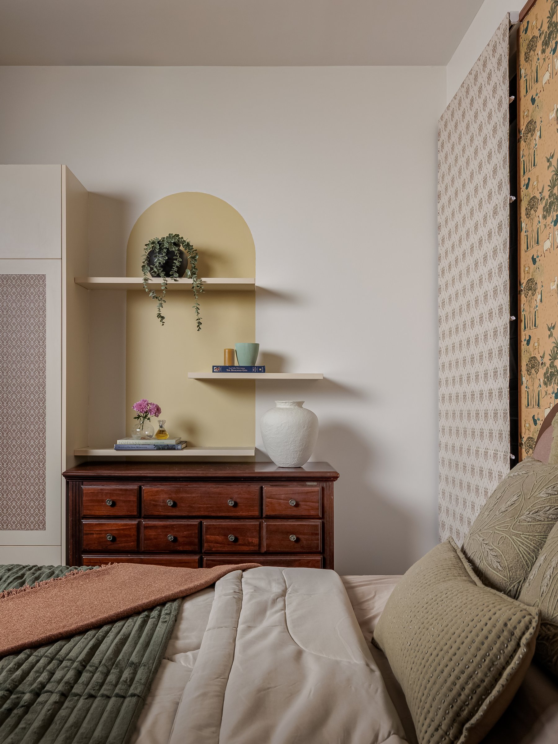 The dressing corner, where a pale-yellow arched niche pairs with a deeper-toned antique chest