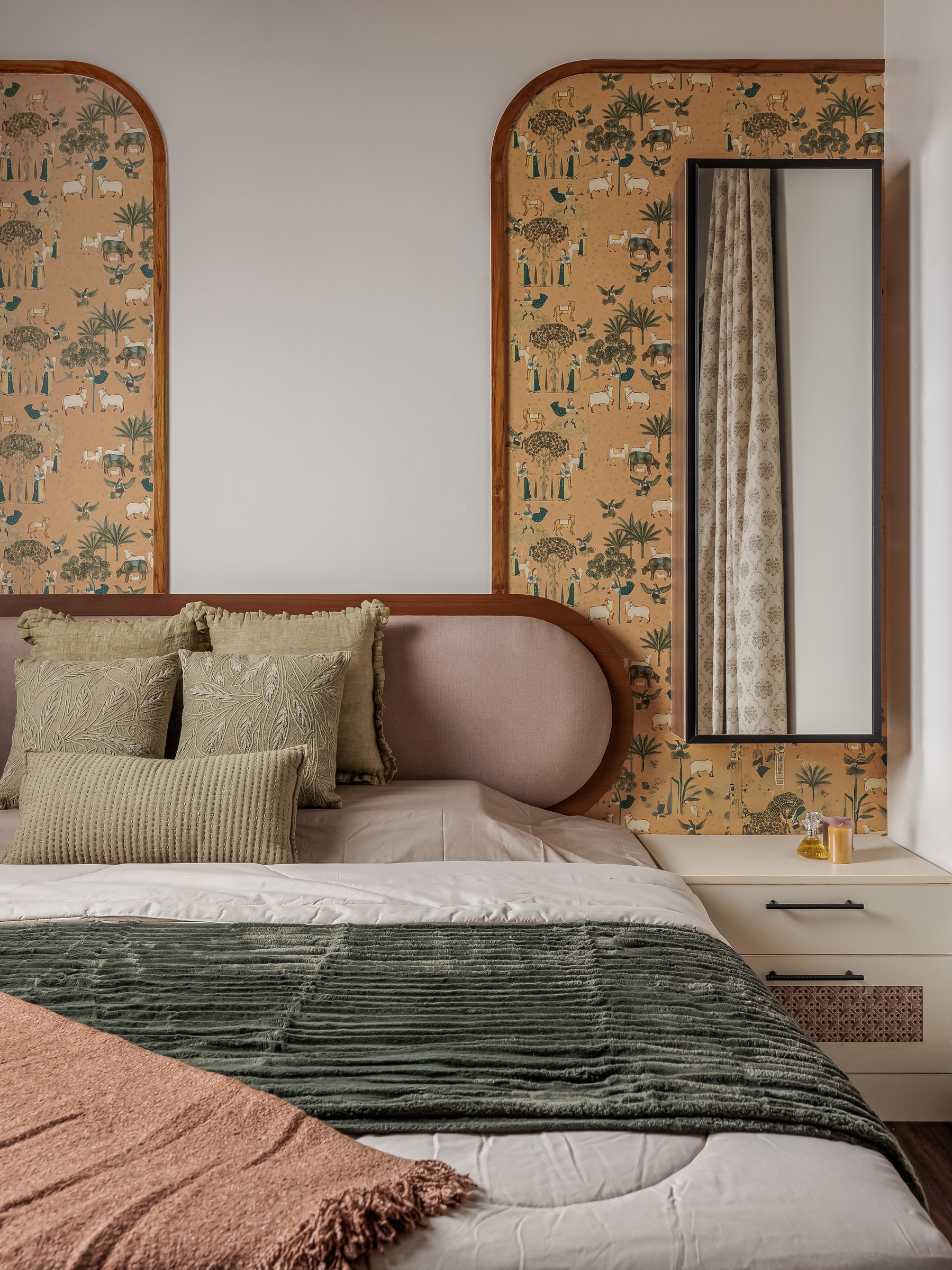 The bed, its capsule headboard in dusty pink softened by a full-height mirror set into the arched panel