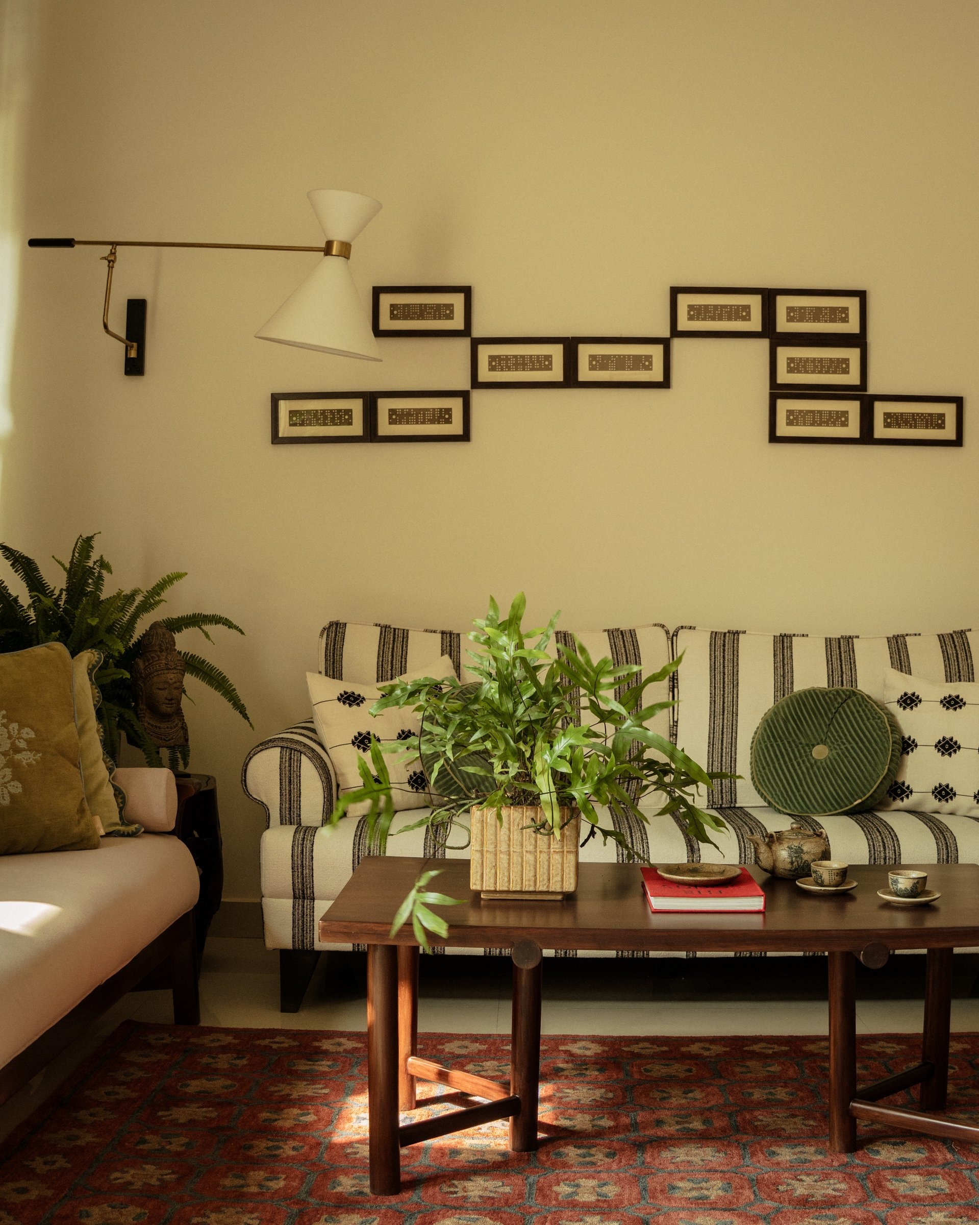 The salon-like gathering space, where a daybed and sofa face each other across the coffee table, with reassembled weaving punch cards arranged on the wall above