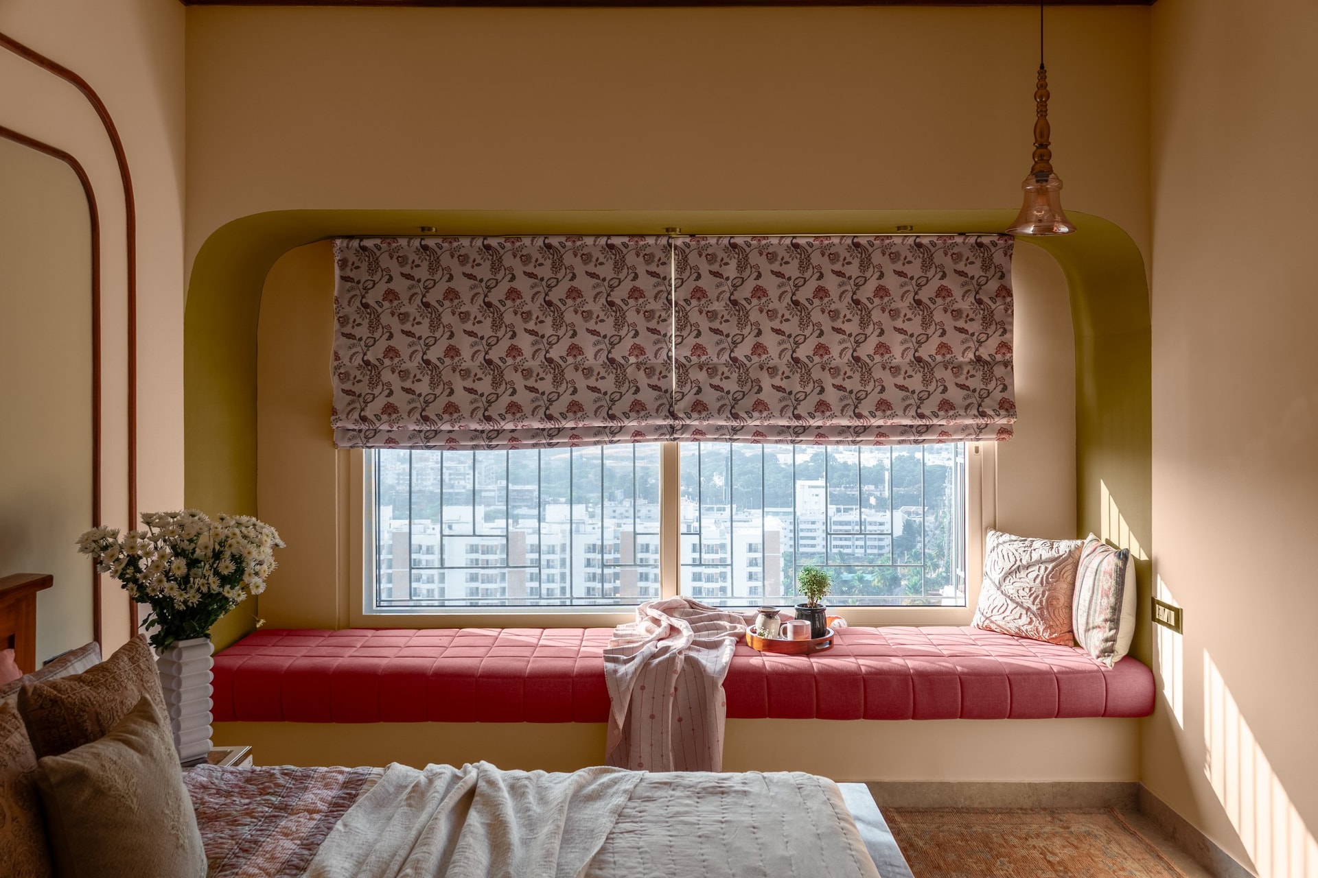 The master bedroom's bay window, where a deep arched niche in mustard tones holds a generous coral-upholstered seat