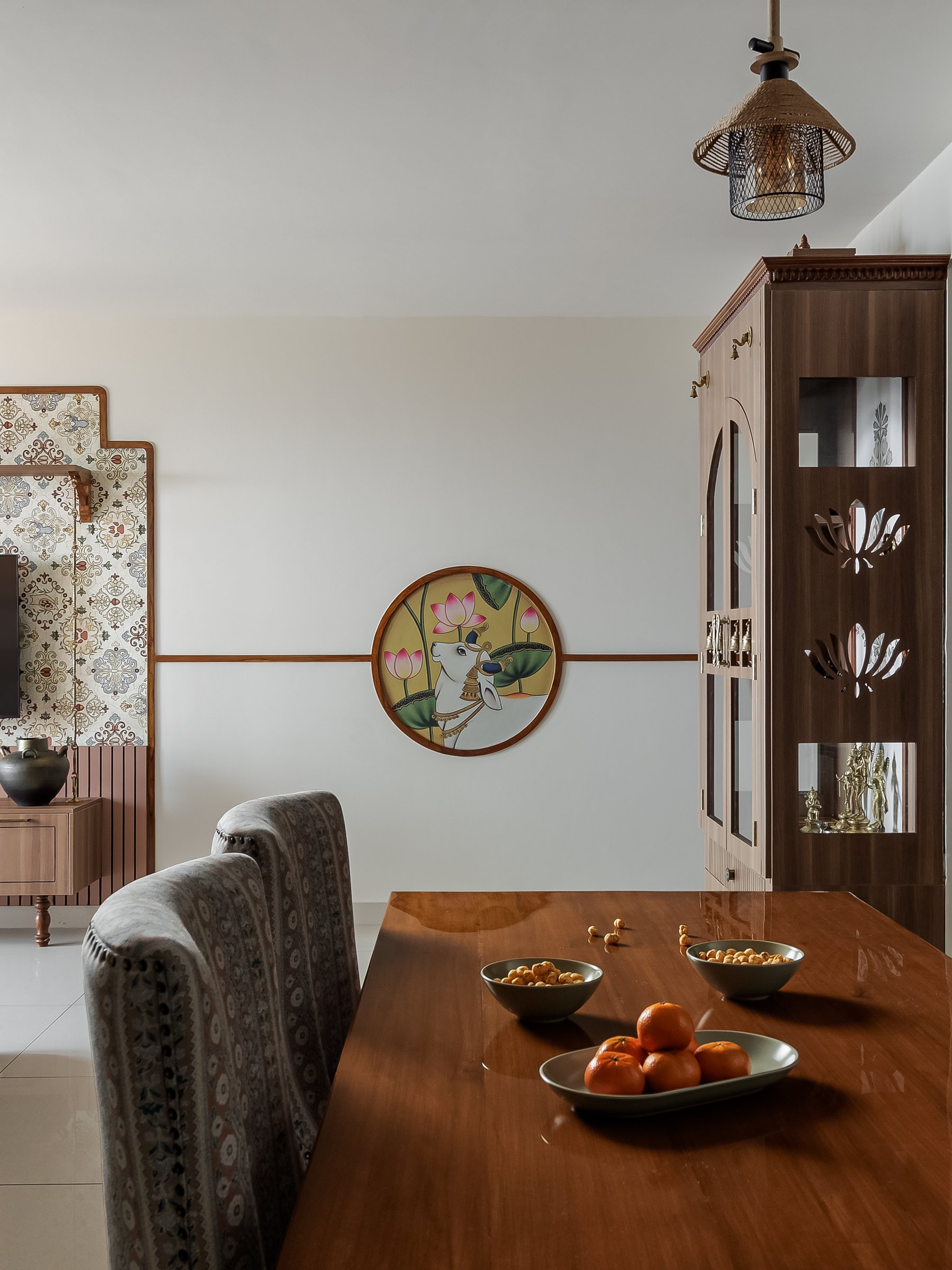 The living room, where a circular Pichwai-style painting anchors the wall between the media unit and dining zone