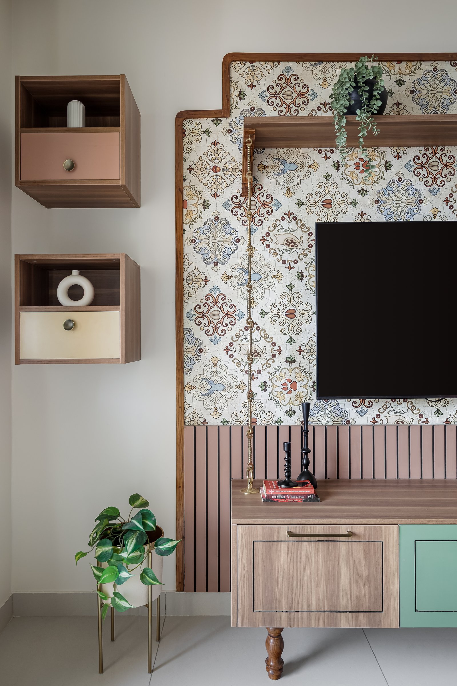 The media wall, where a patterned wallcovering framed in stepped wood is grounded by a fluted pink panel