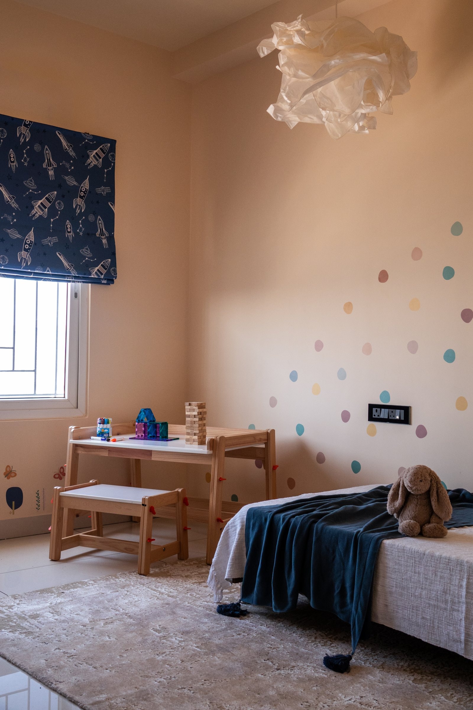 The kids room, where hand-painted pastel dots and a sculptural pendant establish a playful yet restrained atmosphere