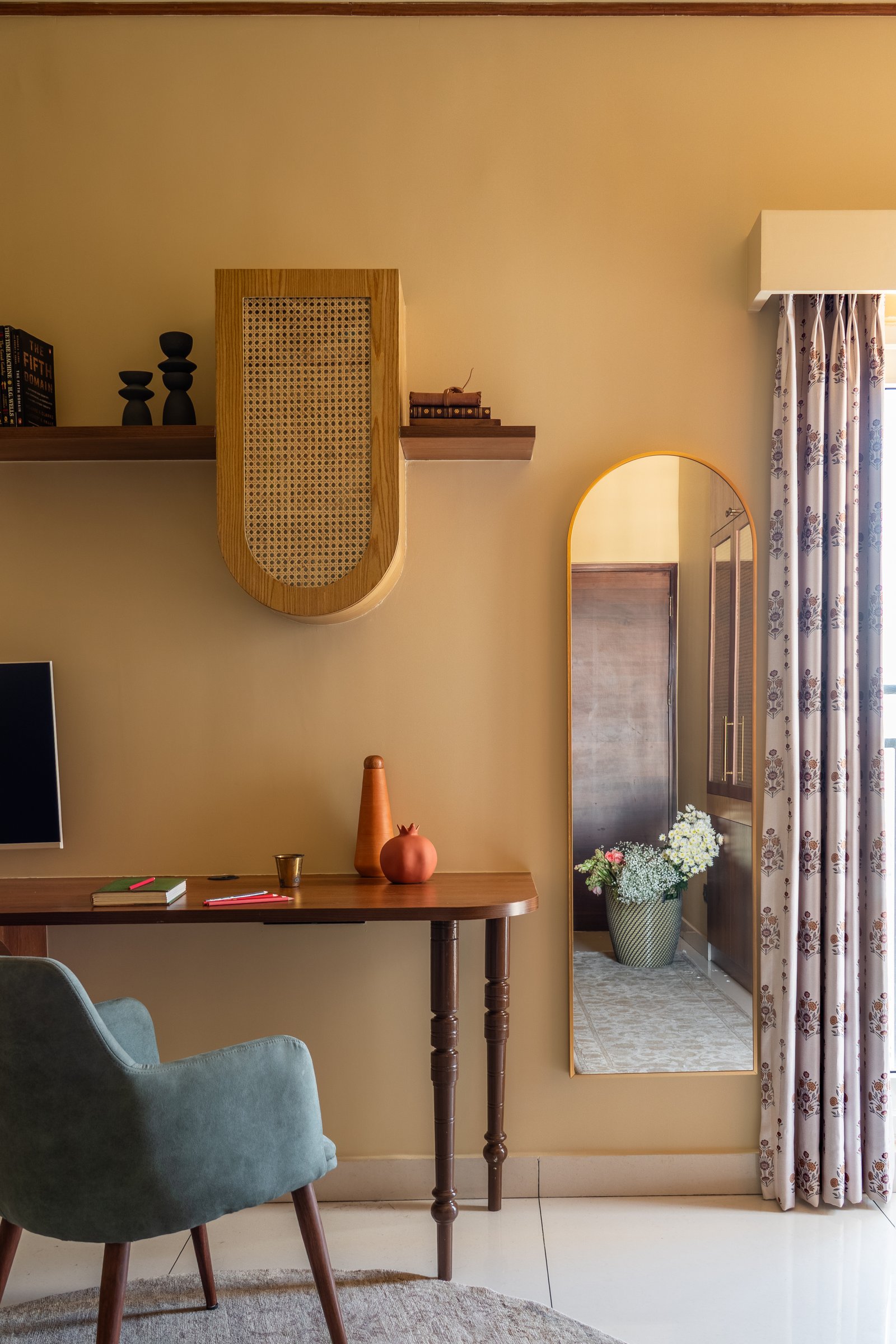 A second view of the study, where a cane-fronted arched panel and a tall arched mirror echo the home's recurring silhouettes