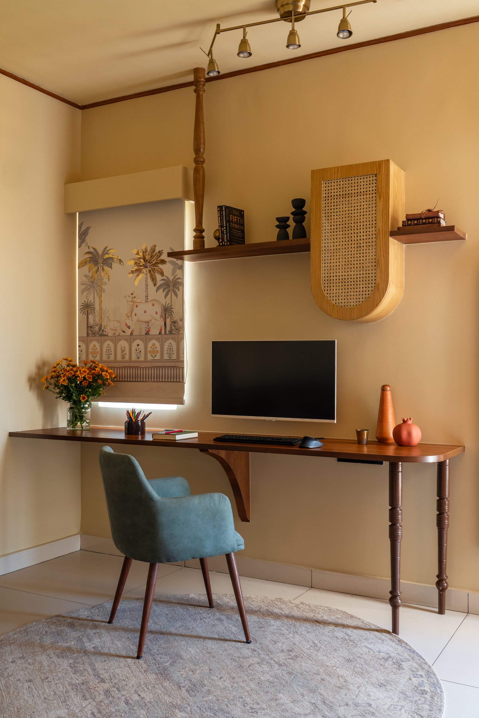The work corner, where a track of brass spotlights and a pastoral printed blind bring warmth to a small dedicated study