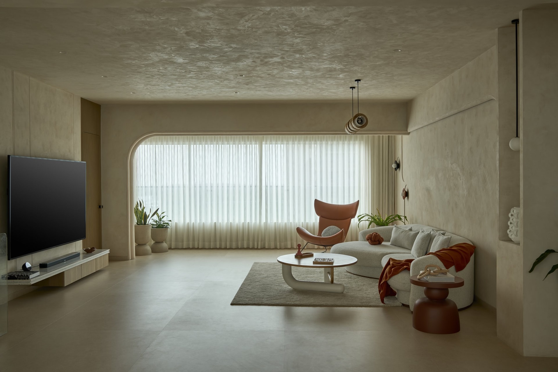 The living room, where a curved arched window and a hand-worked plaster shell frame the seating below