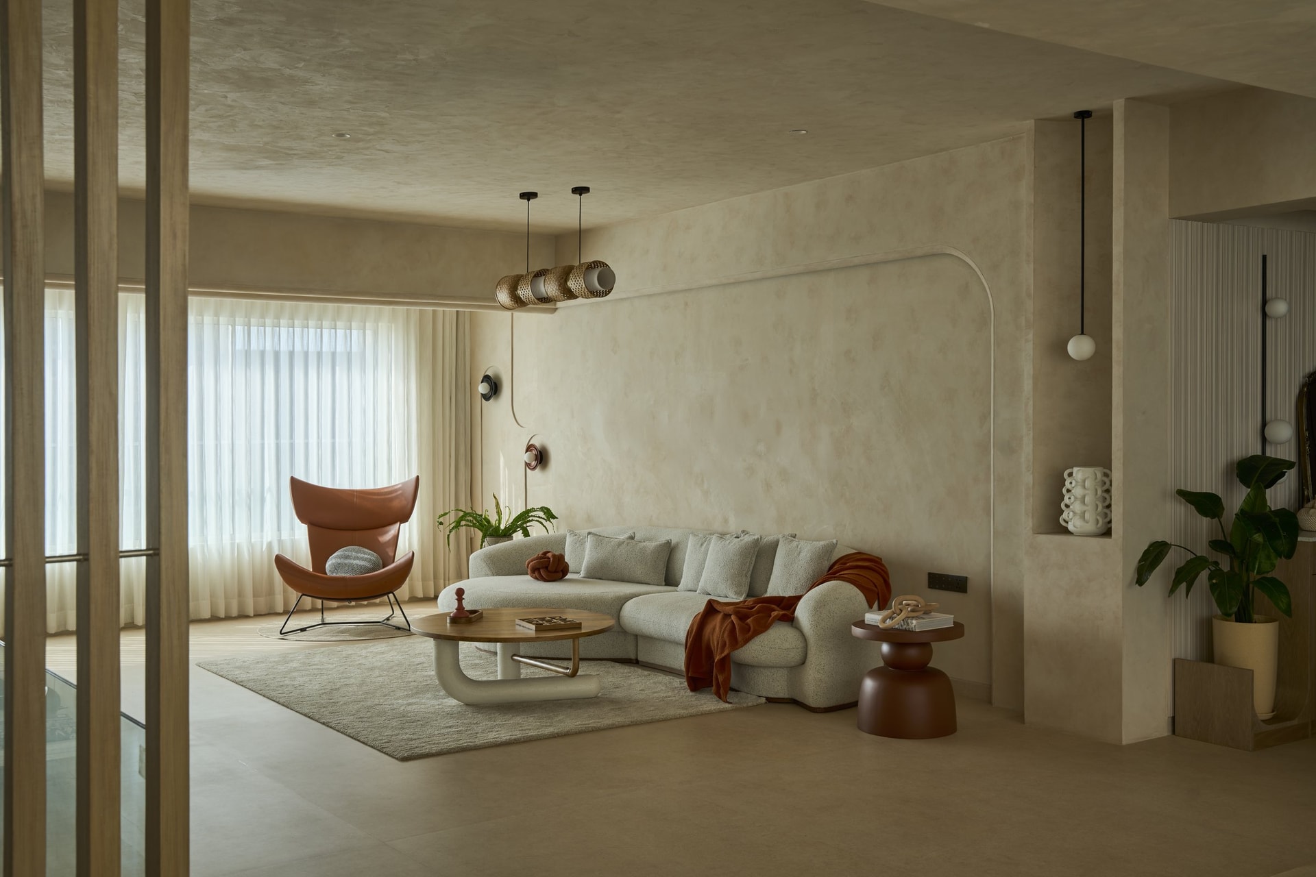 The living area: a curved bouclé sofa and rust-toned lounge chair holding a measured dialogue between softness and structure