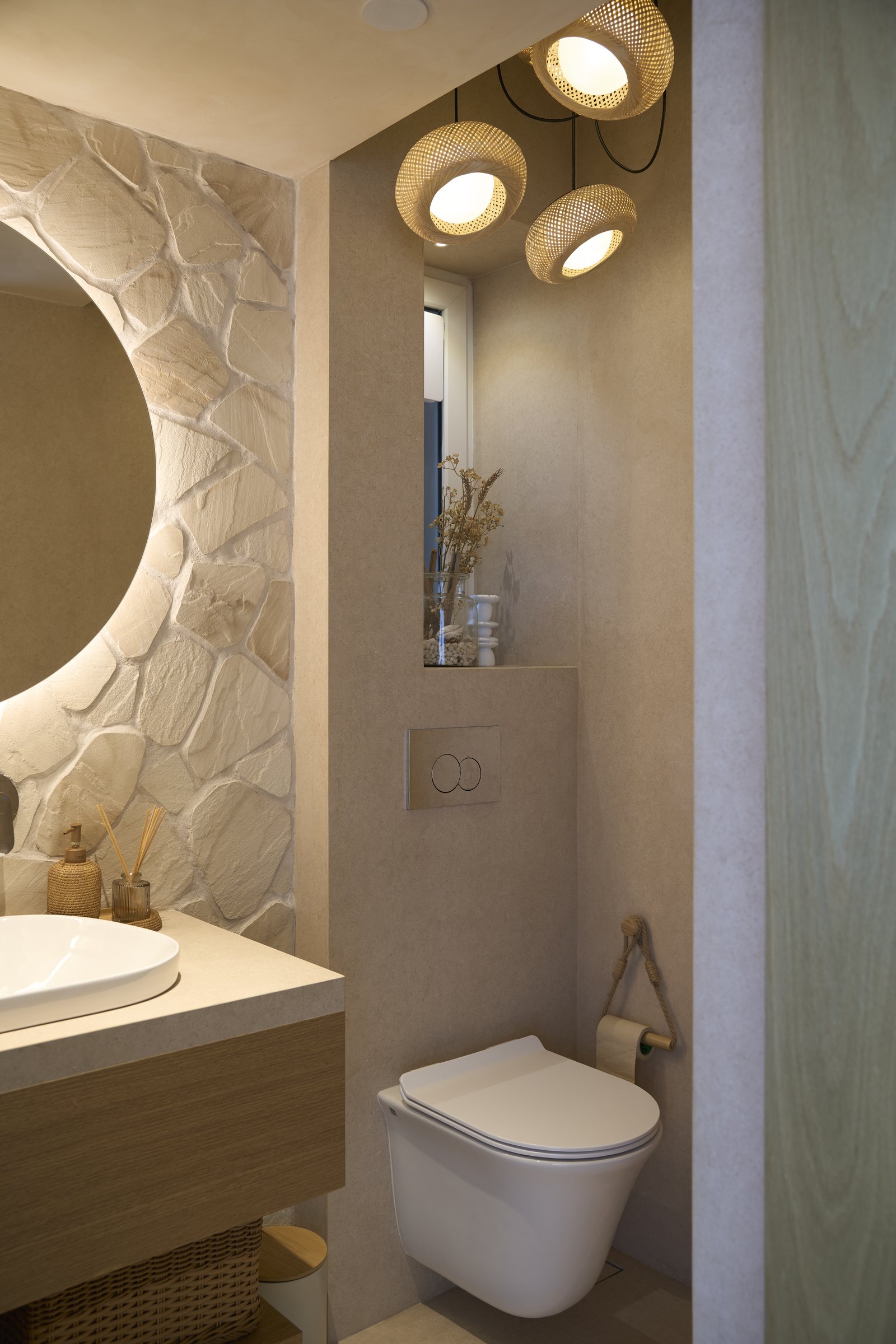 The powder room, where a rubble-stone wall meets a cluster of woven pendants