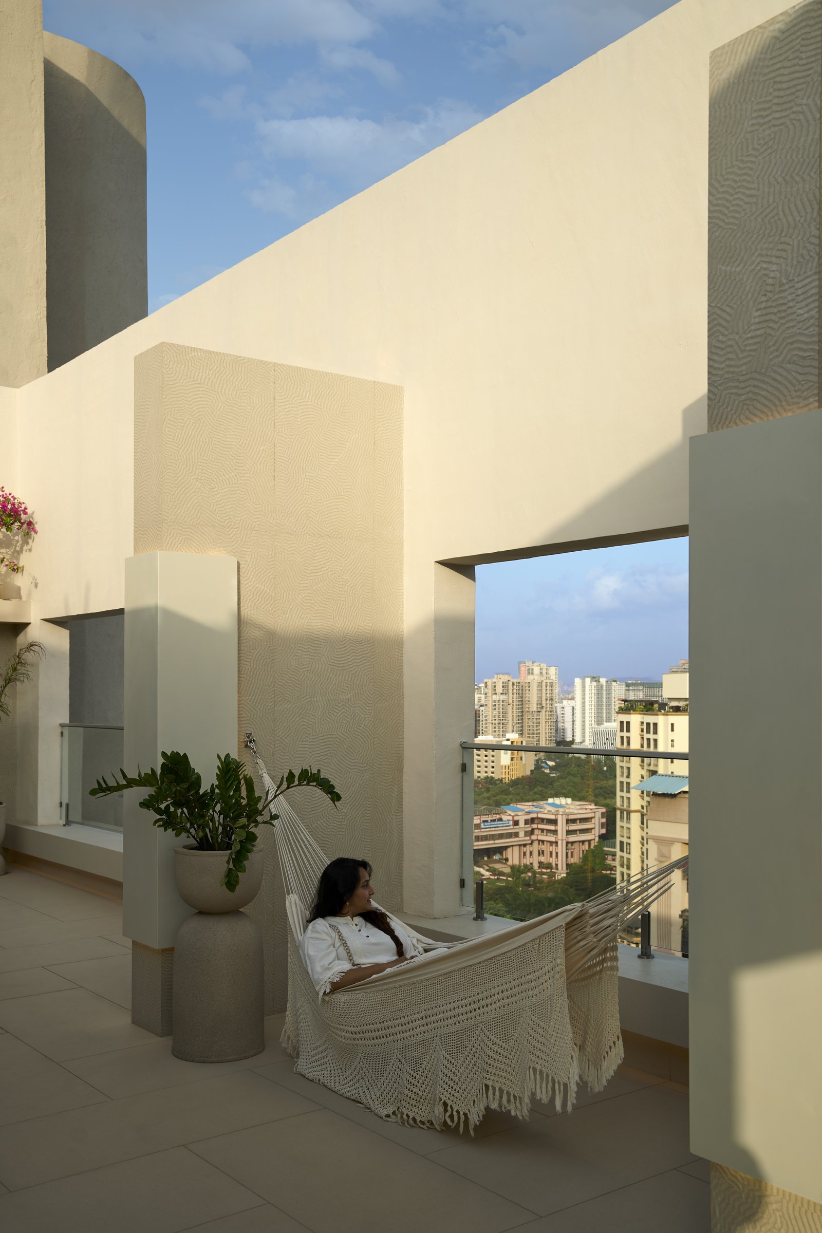 The terrace, where a woven hammock frames a deliberate aperture onto the city skyline