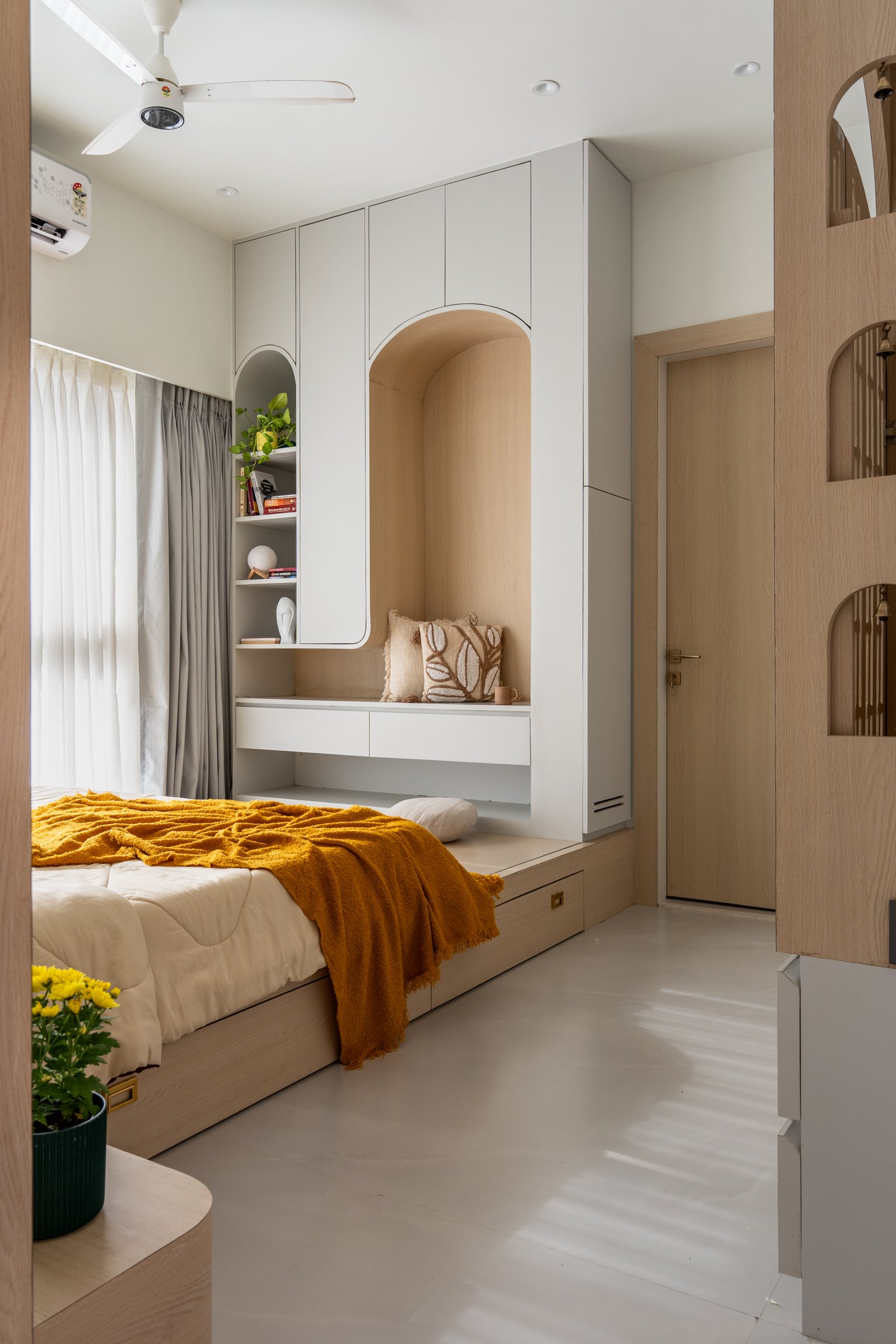 The master bedroom's bespoke wall, where a book niche, display shelf, and vanity-cum-reading nook fold into a single arched composition