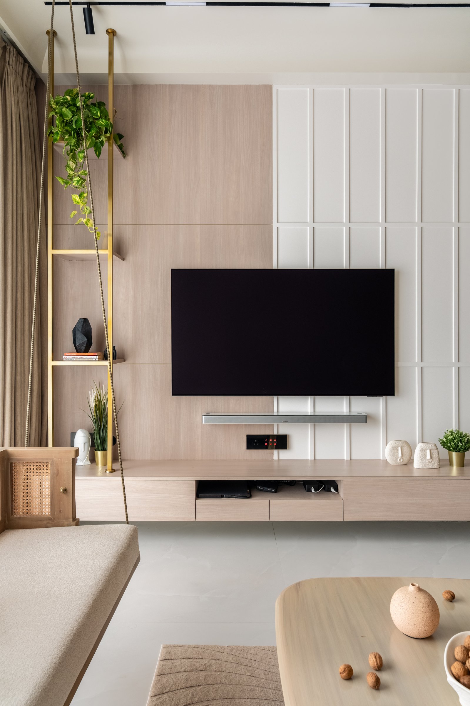 The living room shelving unit, a slender brass and wood column that mediates between the two panelling systems on the media wall