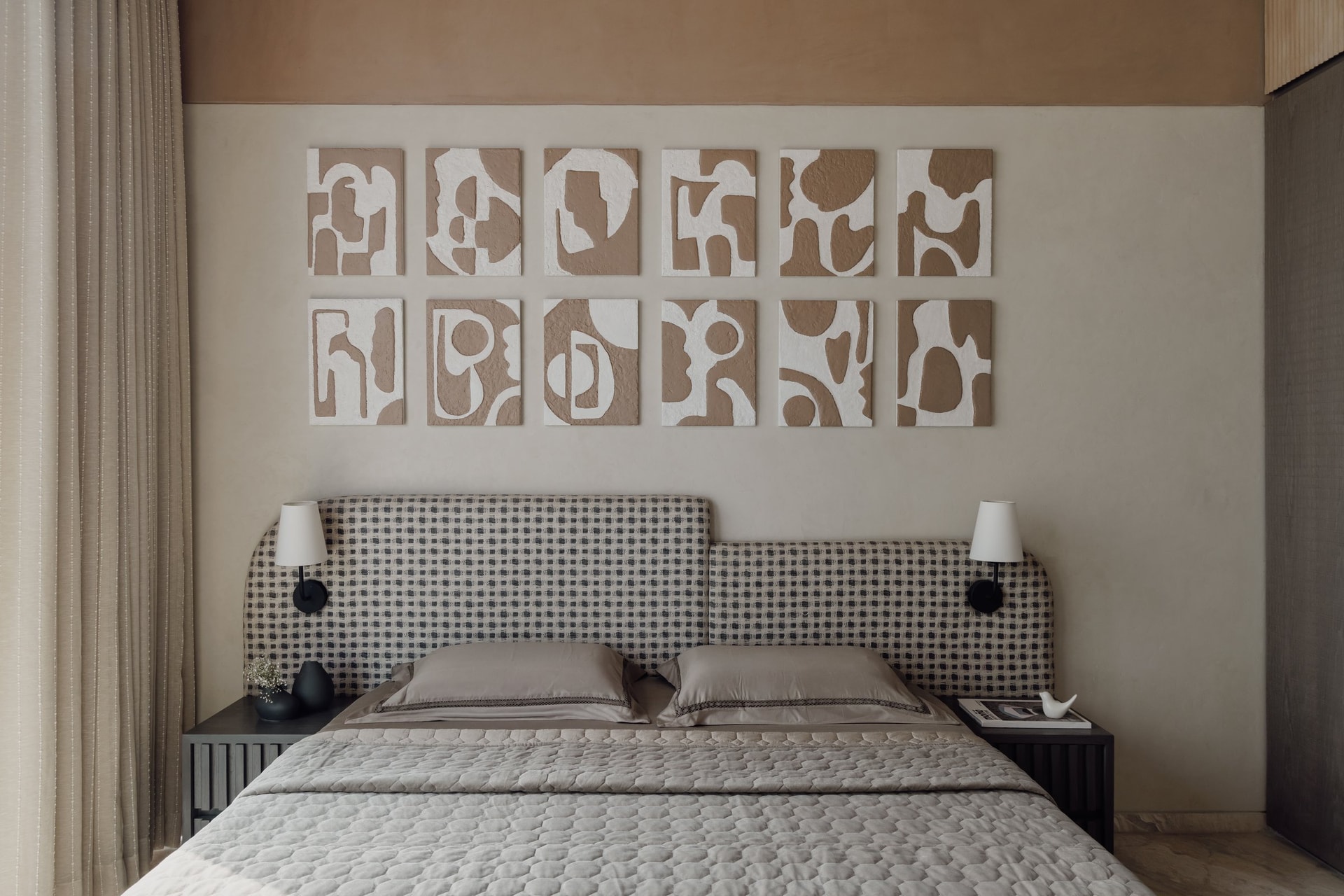 The guest bedroom, where a grid of twelve hand-worked panels in plaster and taupe forms an abstract composition above a checkered headboard