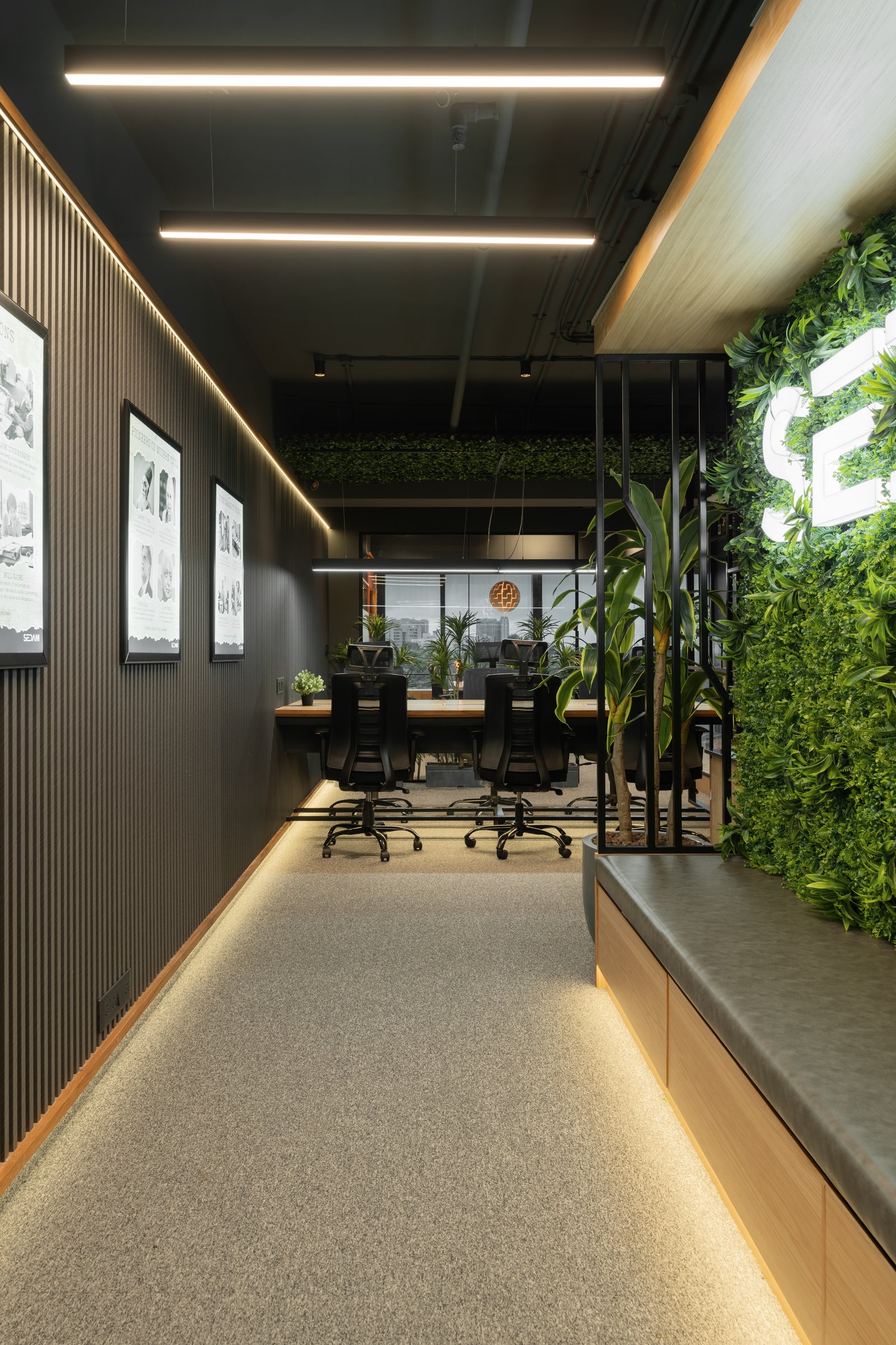The corridor to the meeting rooms, where framed prints and a vertical green wall carrying the signage set the arrival tone
