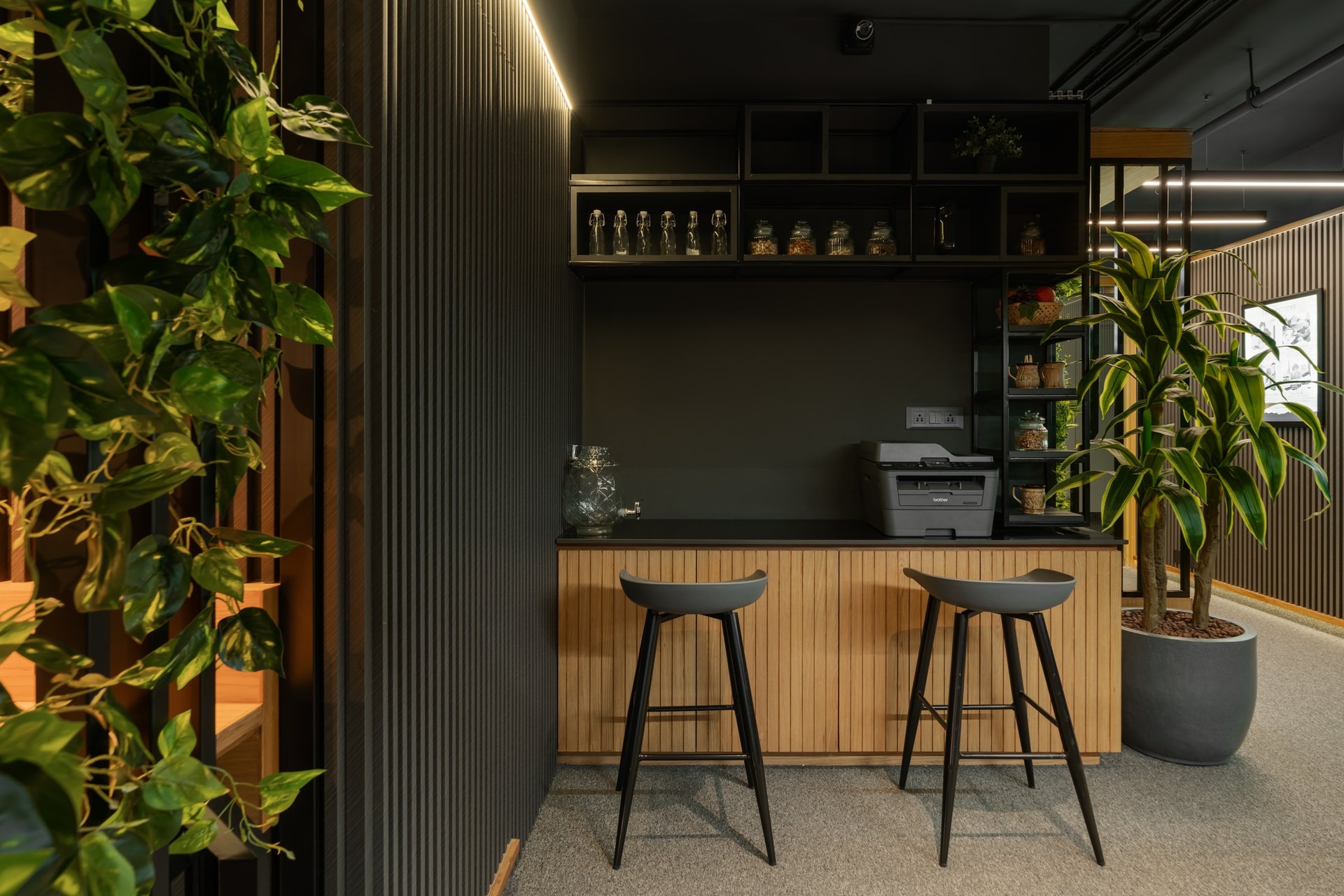 The pantry, where fluted blond wood cabinetry and open black shelving meet a soft veil of trailing greenery