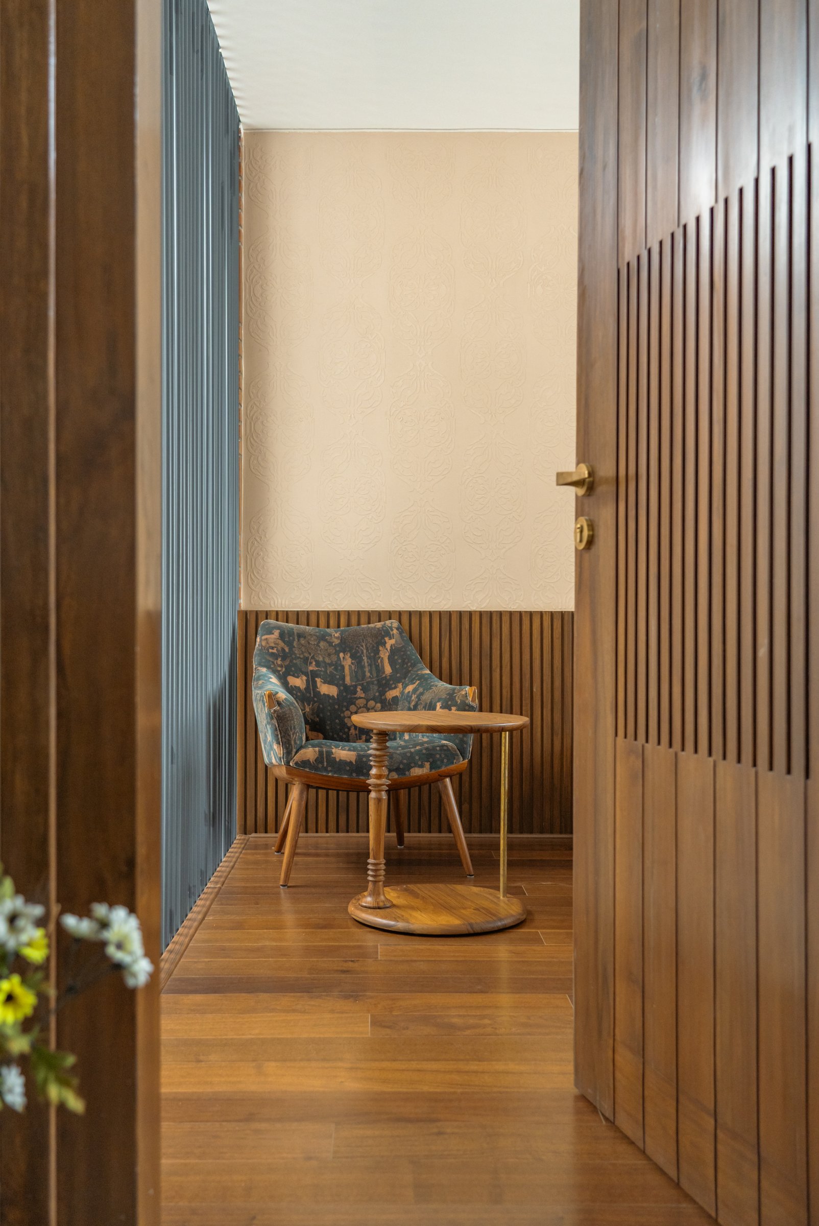 The dressing corridor off the primary bedroom, lined with slatted timber cabinetry and terminating in a small seating vignette