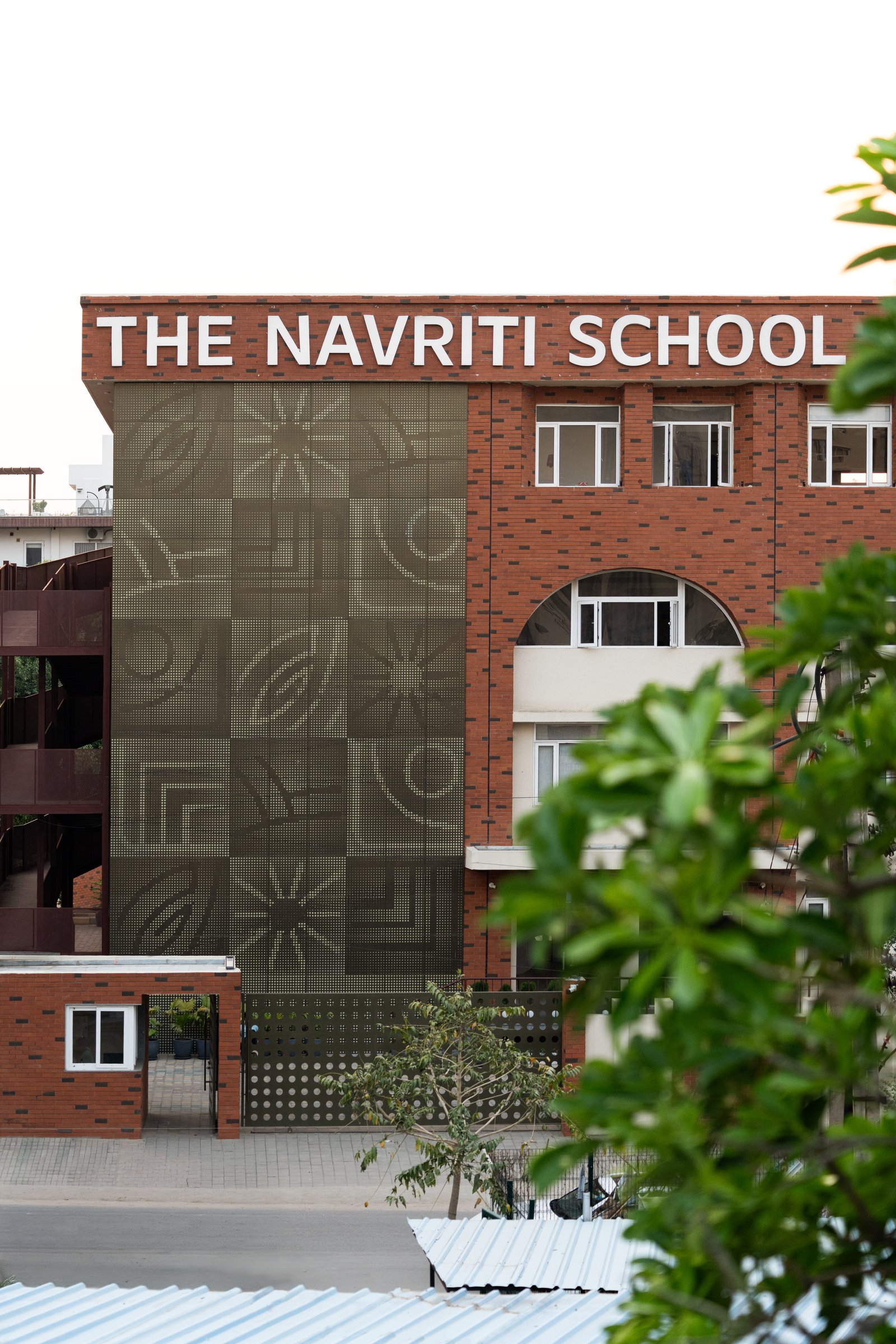A closer view of the perforated graphic panel, where circles, arcs and geometric emblems sit within the brickwork like a textile field