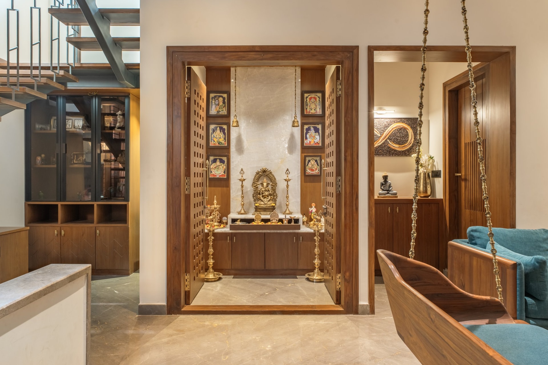 The pooja niche, framed as an architectural moment with carved lattice doors and a pale stone-clad interior