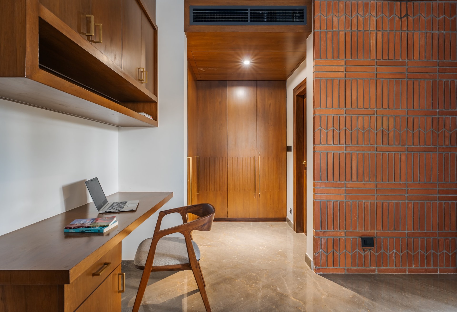 The study, where a long timber desk faces a wall of perforated terracotta brick that borrows light from the adjoining volume