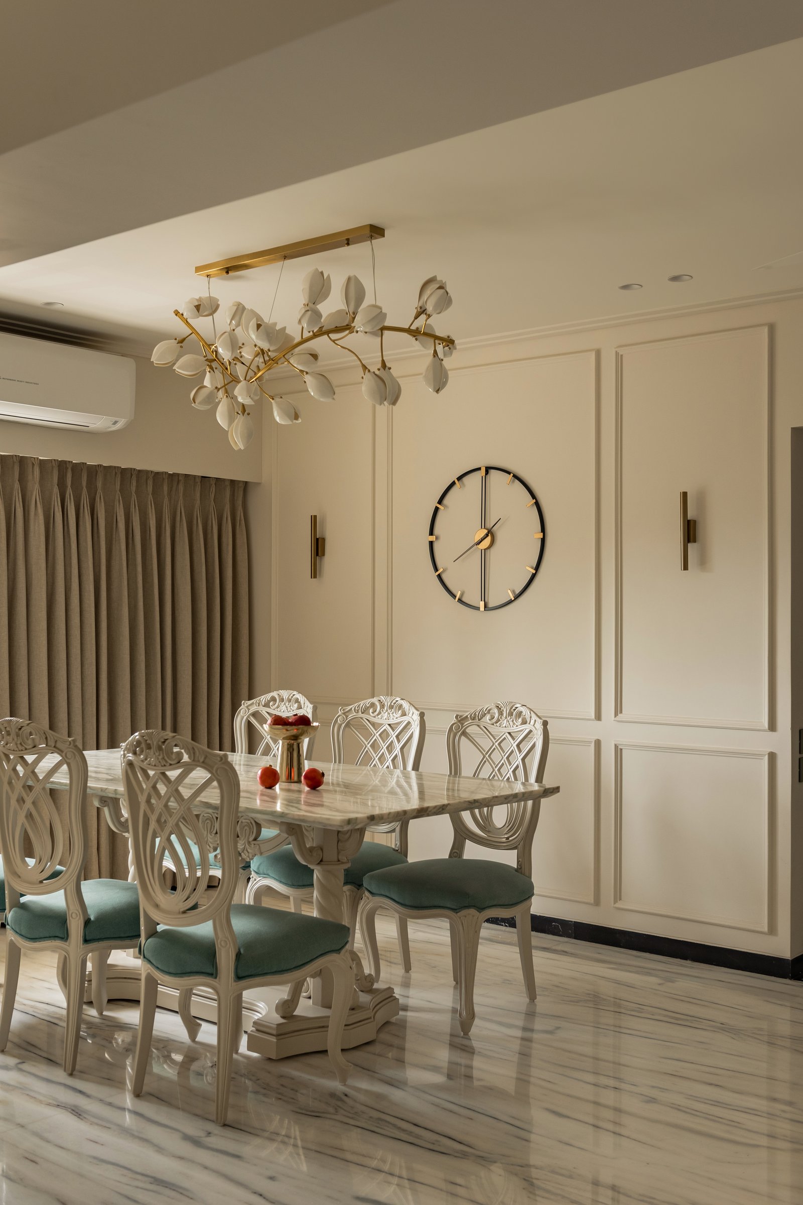 The dining area, anchored by a ceramic-and-brass chandelier and a marble-topped pedestal table