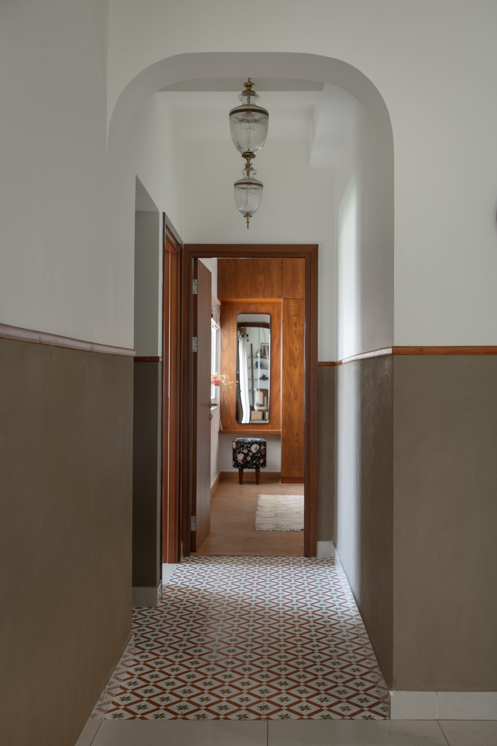 The passage to the bedrooms, lined with encaustic-style tiles and lit by glass-and-brass pendant lanterns