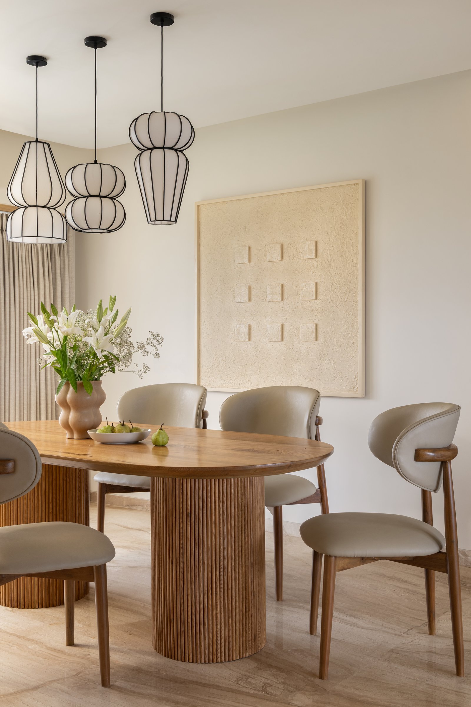 The dining area, anchored by the ribbed pedestal base of the oval timber table
