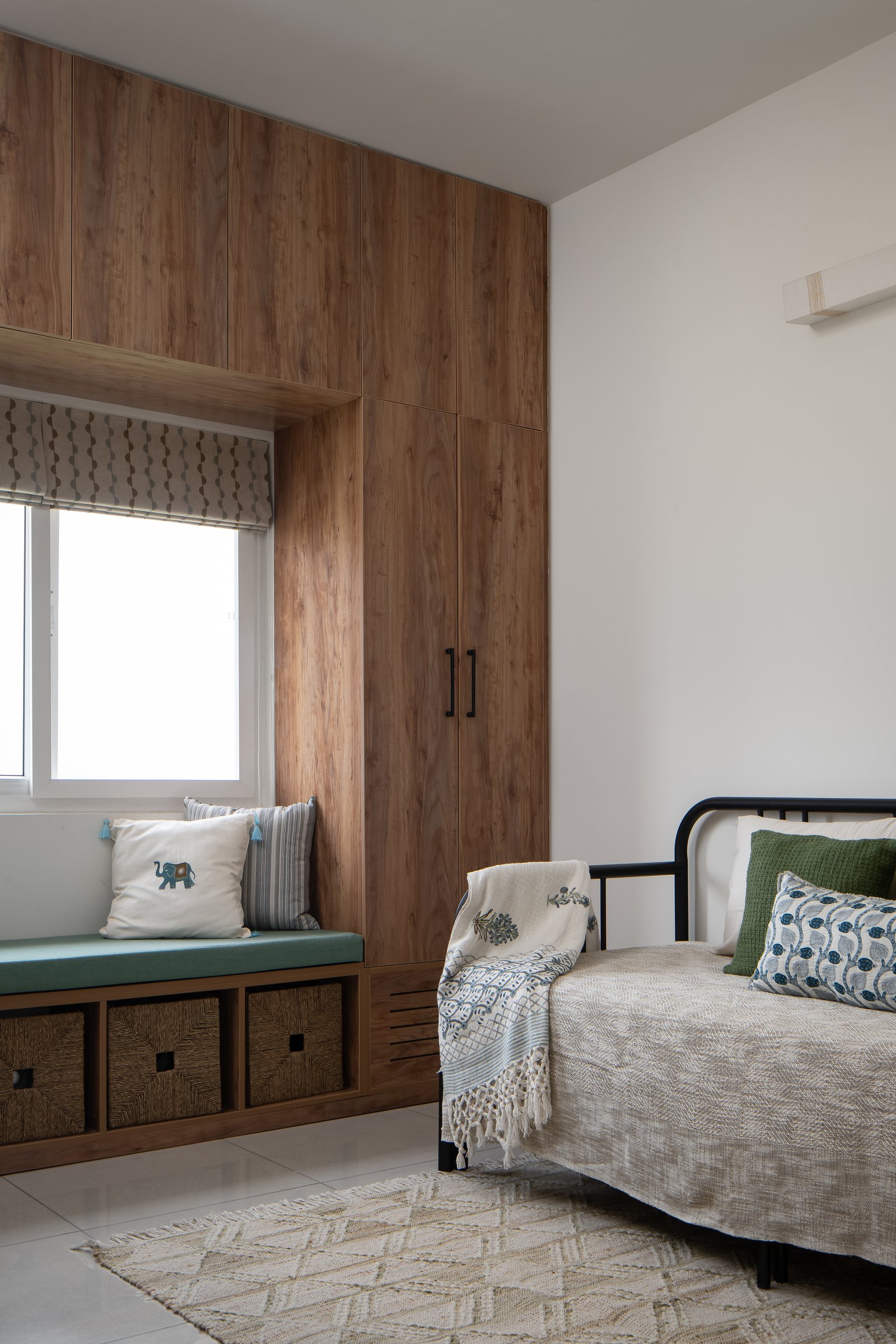 The guest bedroom, planned around a window seat with woven storage and a metal-framed daybed