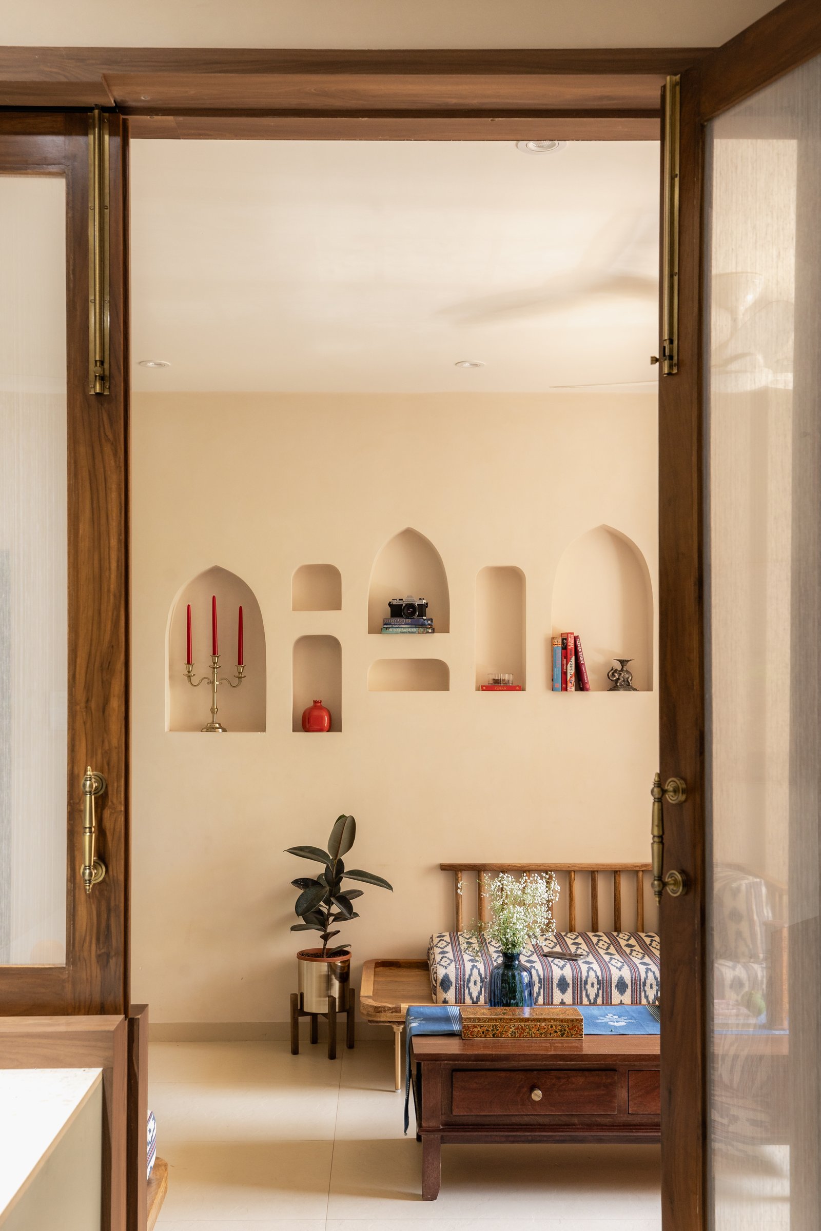 The living room framed through its threshold, with a wall of arched niches beyond