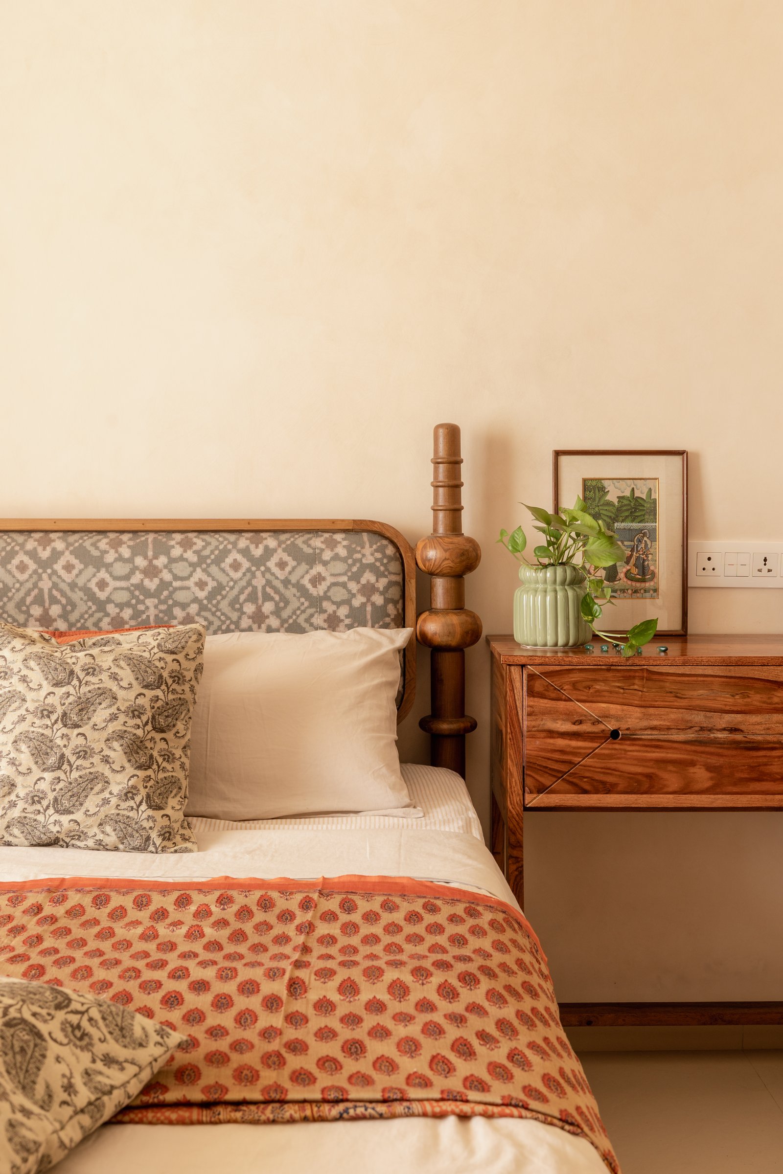 A closer view of the bed, its low ikat headboard framed in wood beside a grained wooden nightstand