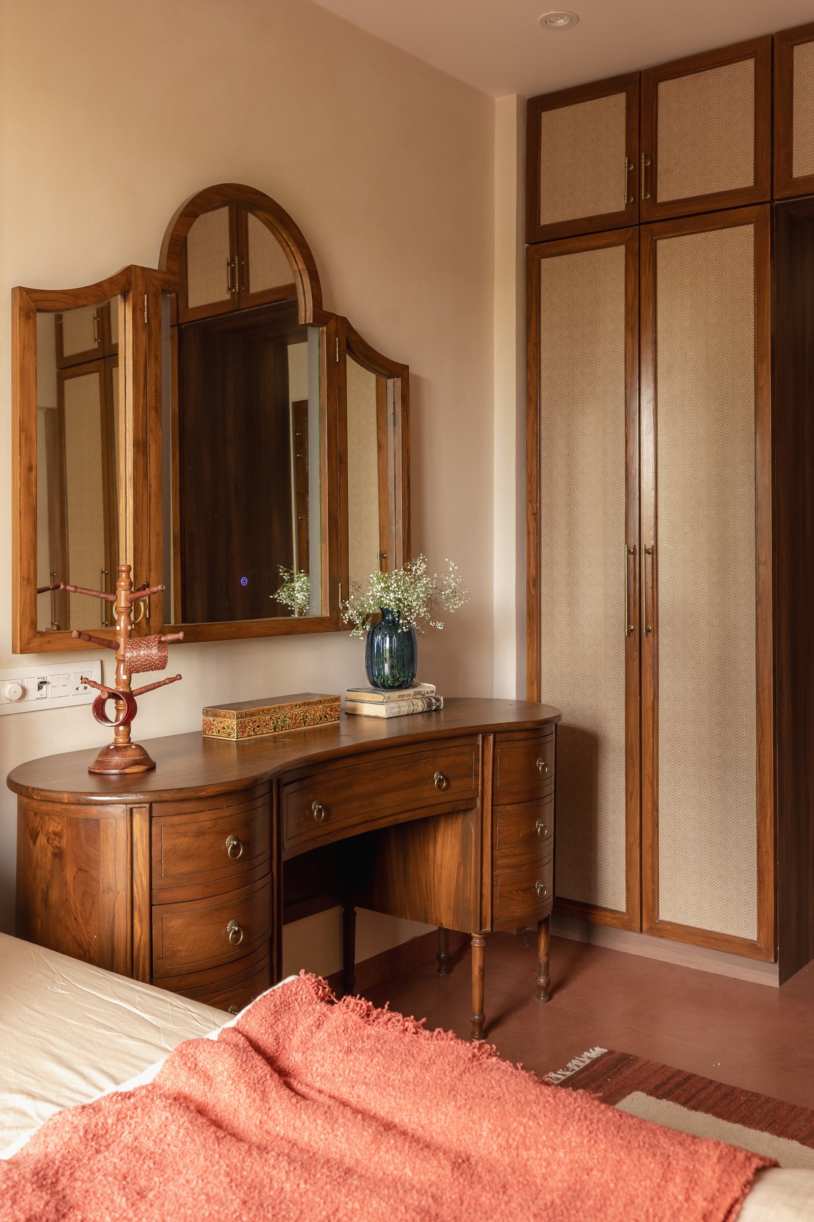 A curved dressing table and a full-height wardrobe fronted in woven-cane inserts
