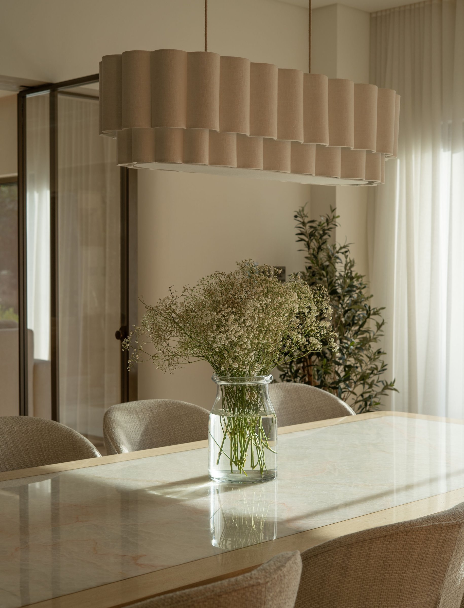 A pleated pendant and glass jar of baby's breath compose a quiet corner of the dining room.