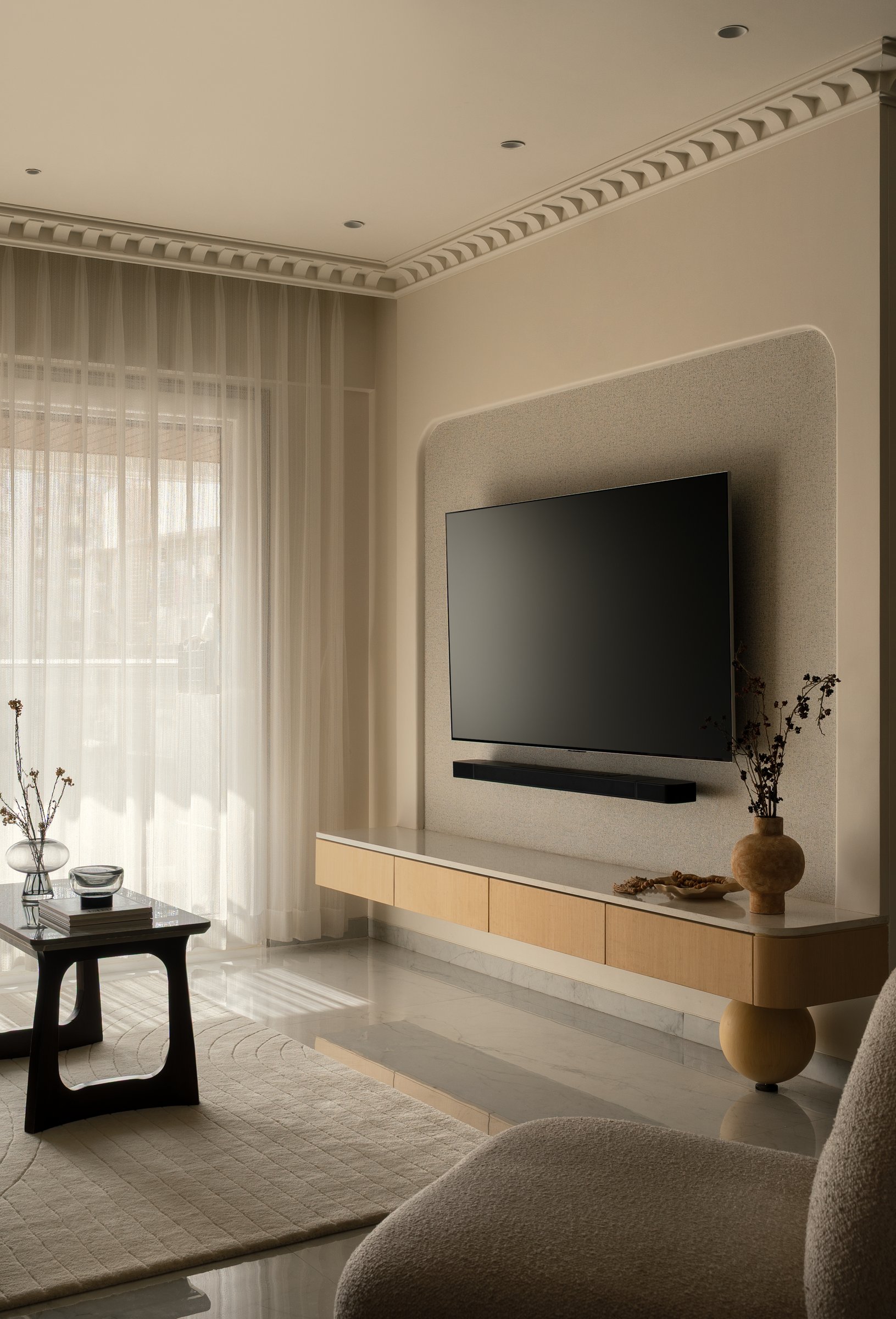 The living room's upholstered arched niche framing the media wall, softened by sheer curtains and a floating cabinet below