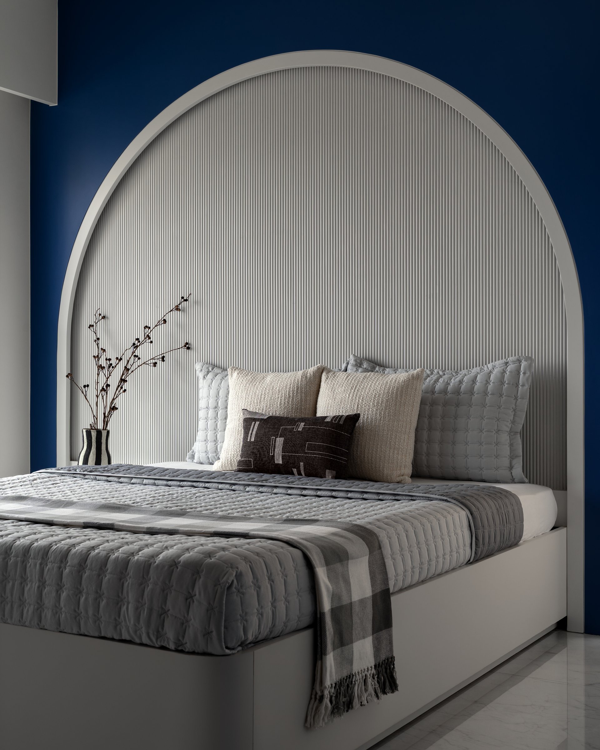 The second bedroom, where a deep blue surround frames a tall arched niche with a reeded ivory interior