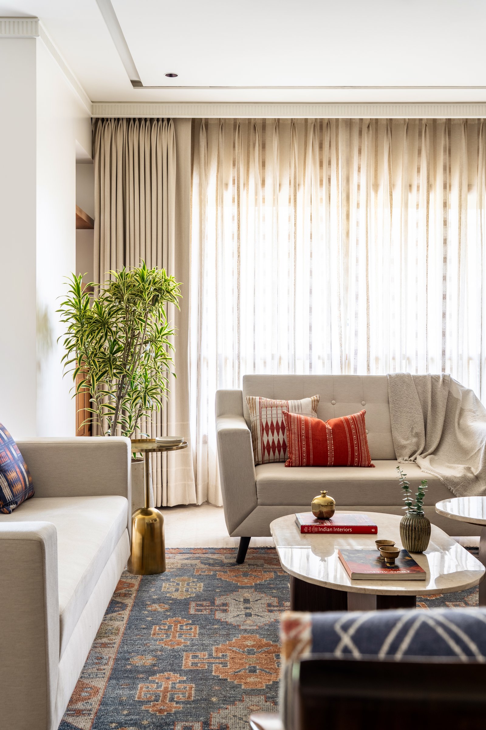 In the living room, layered neutrals and an antique-toned rug allow filtered daylight to become the space's most expressive element