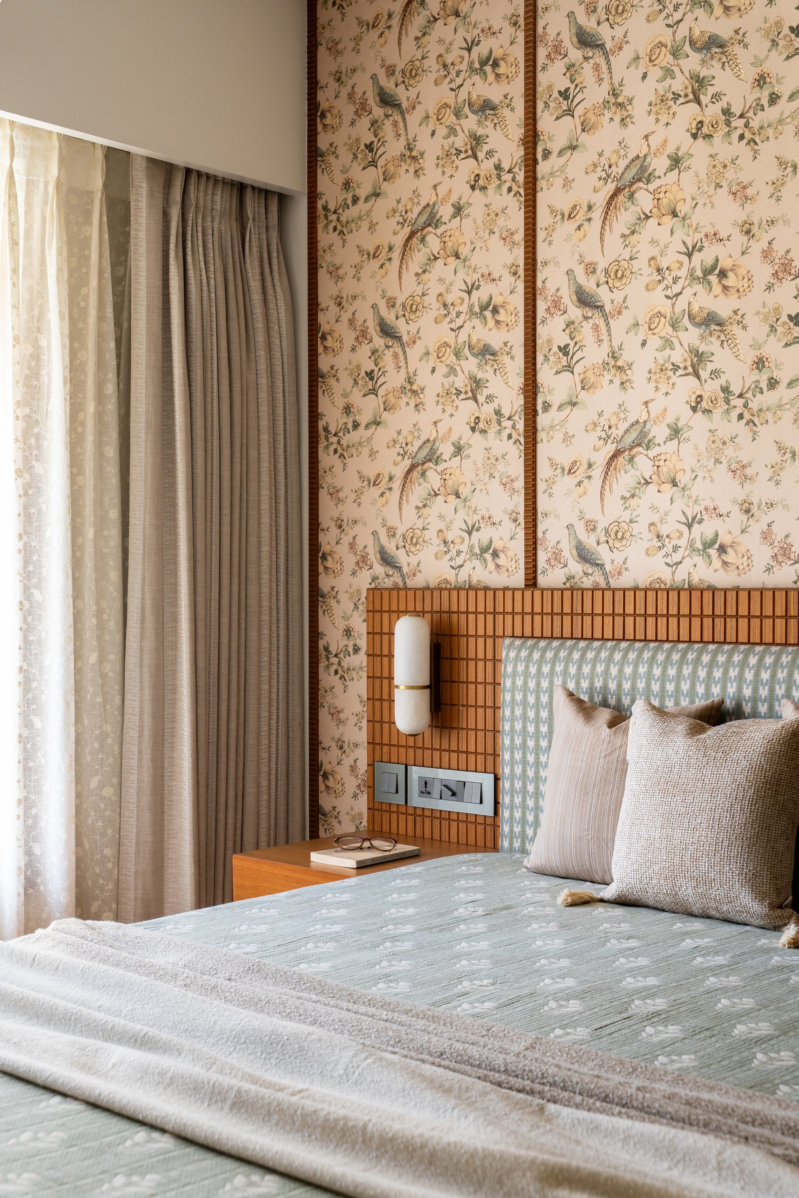In the primary bedroom, a botanical wallpaper of birds and blossoms establishes a softer, more romantic register