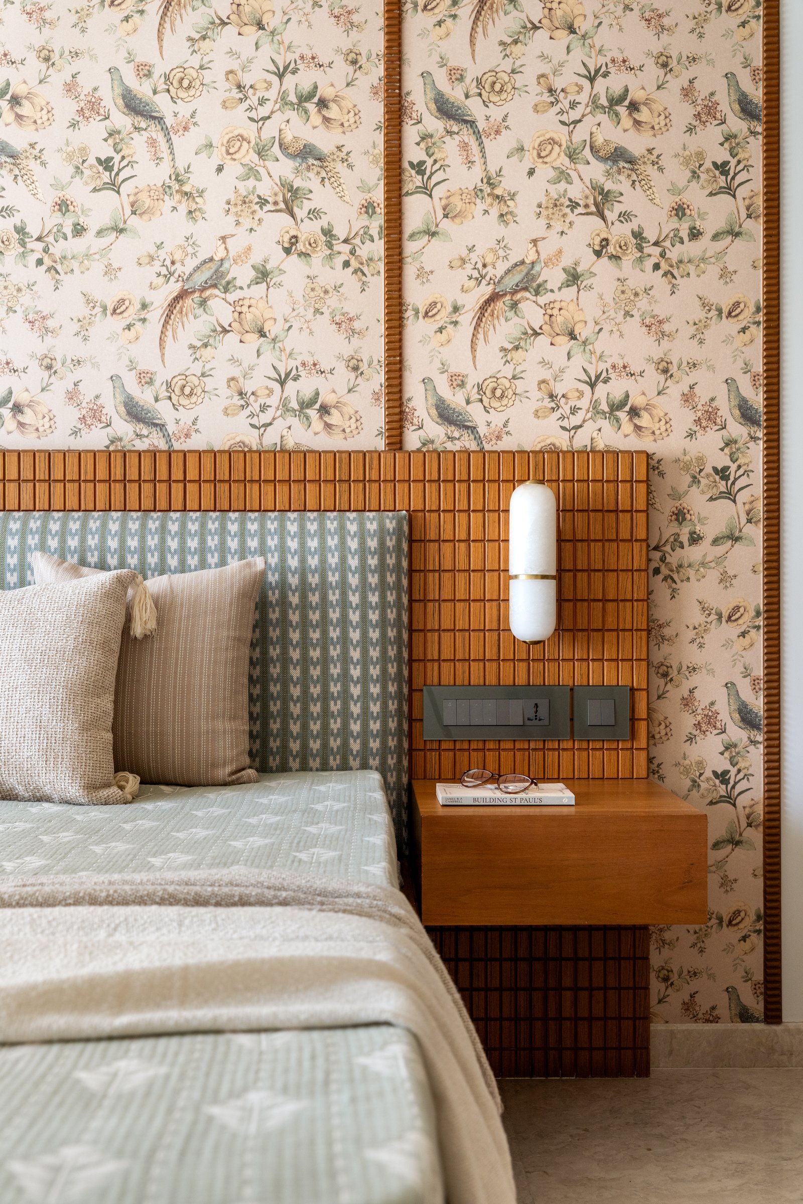 A closer view of the headboard, where a slatted timber panel frames a wall-mounted alabaster and brass sconce